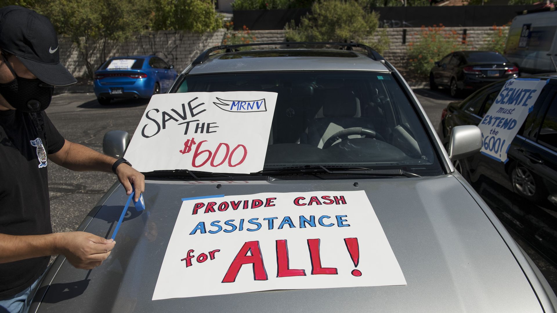 A man tapes signs to his car before participating in a caravan rally down the Las Vegas Strip in support of extending the $600 unemployment benefit, August 6, 2020 in Las Vegas, Nevada