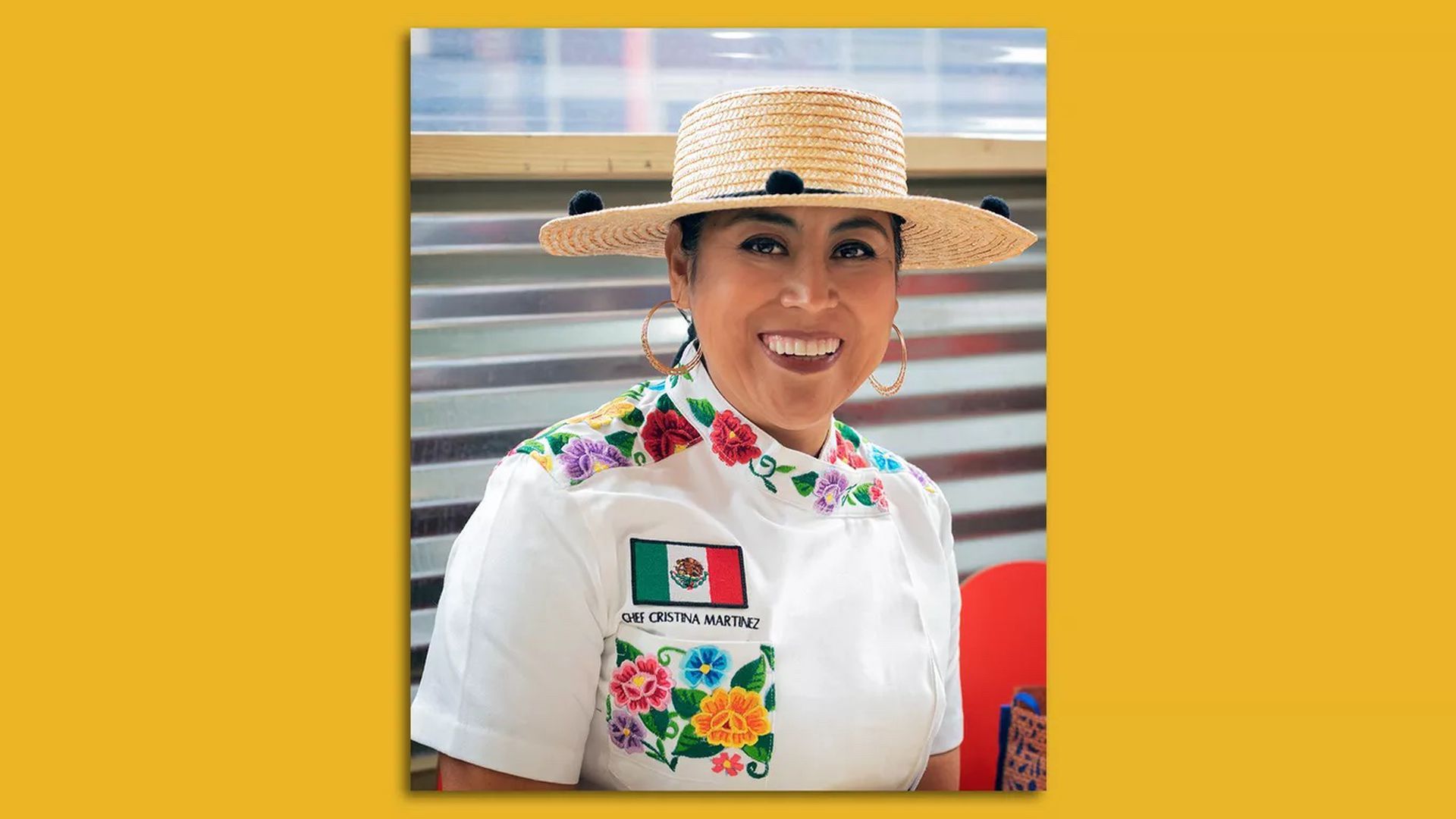 Cristina Martinez smiles wearing a straw hat and an embroidered chef's white coat, with a Mexican flag on the lapel.