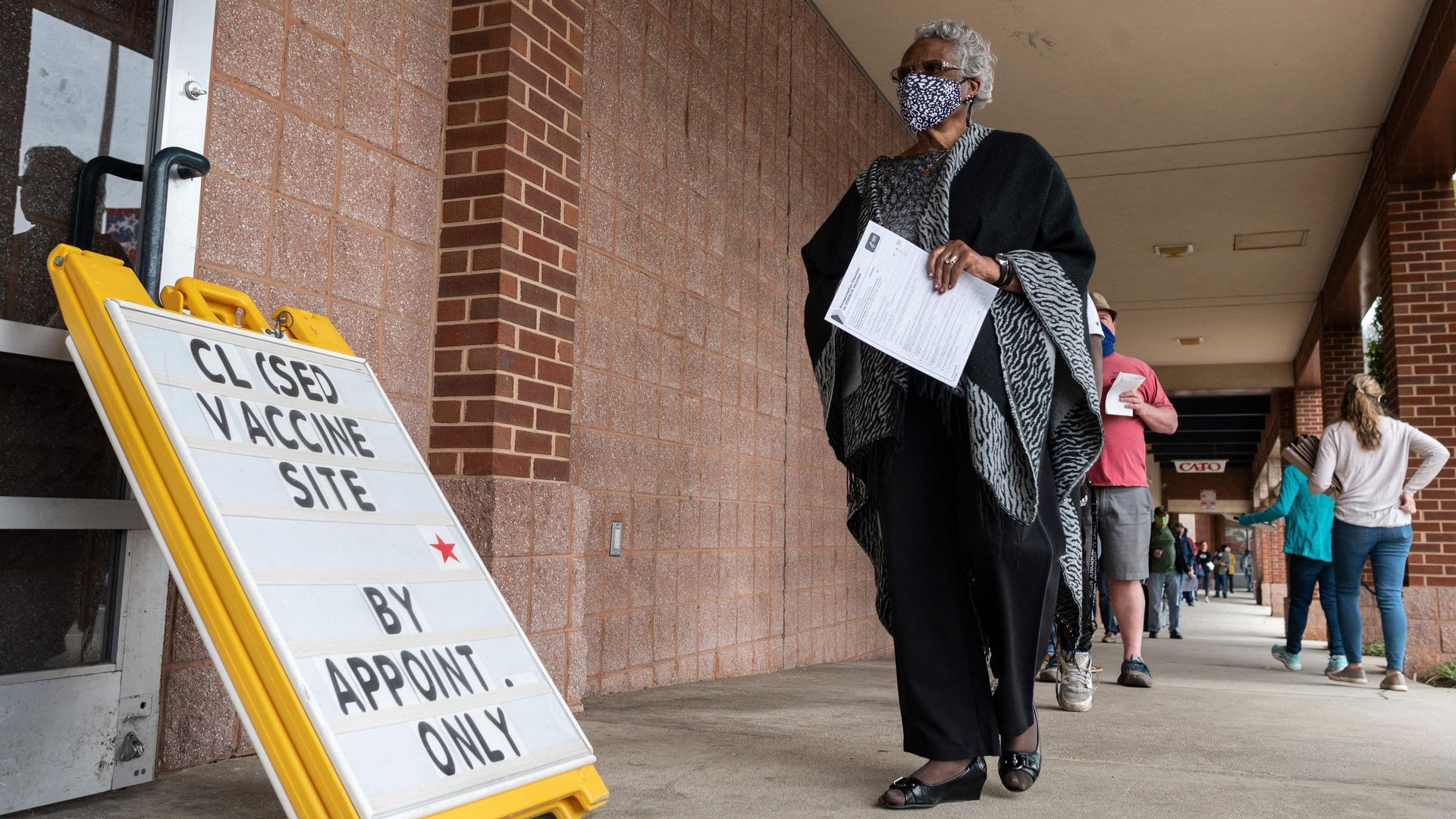Photo of a sign leaning against a building that says "Close vaccine site, by appoint. only"