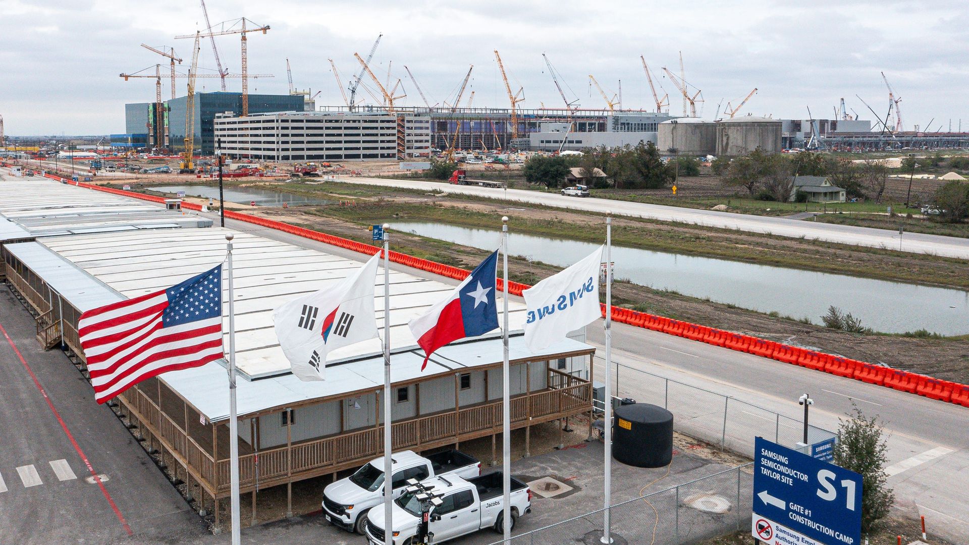An American, South Korean, Texas, and Samsung flag fly in front of construction at the Samsung Austin semiconductor plant in Taylor, Texas.