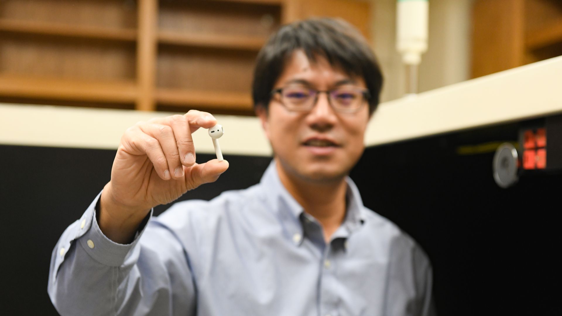 A University of Texas researcher holds up a wireless earbud.
