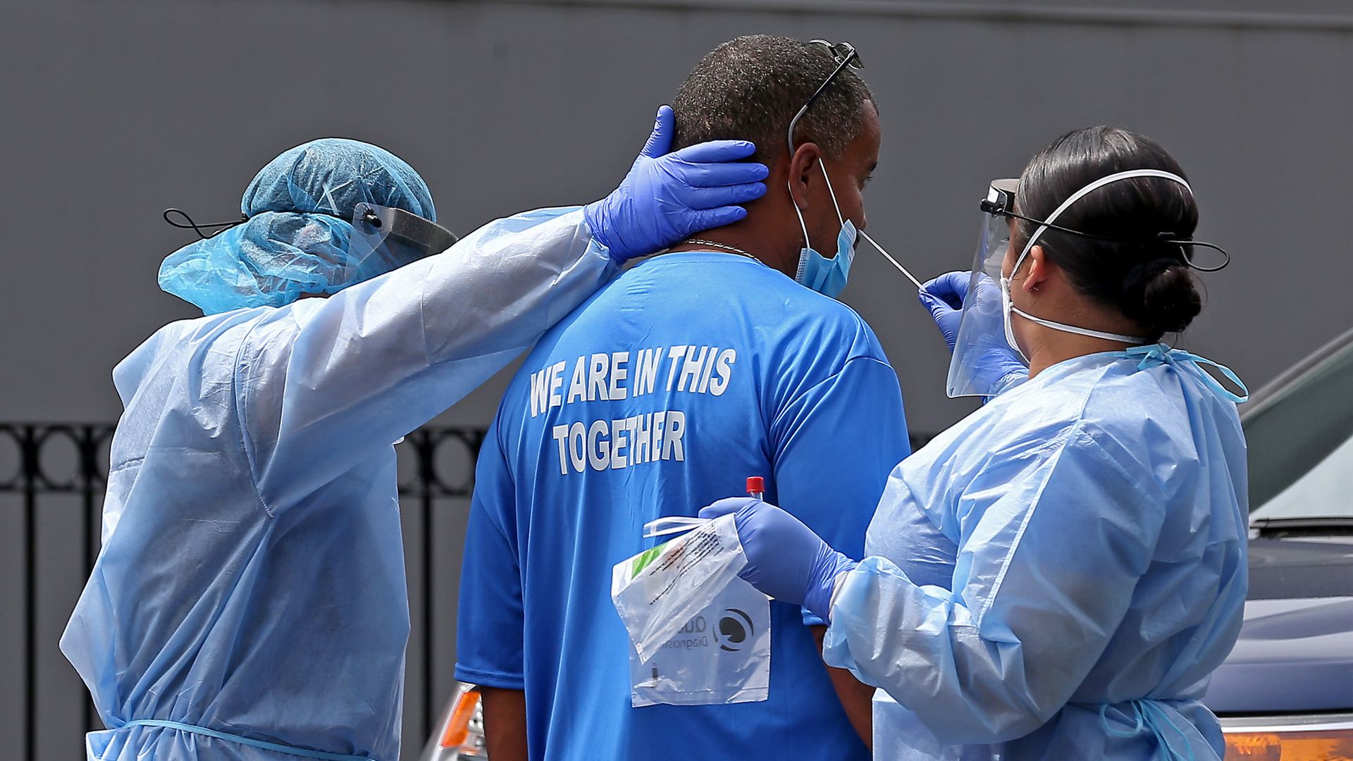 Two medical professional test a man for the coronavirus with a swab