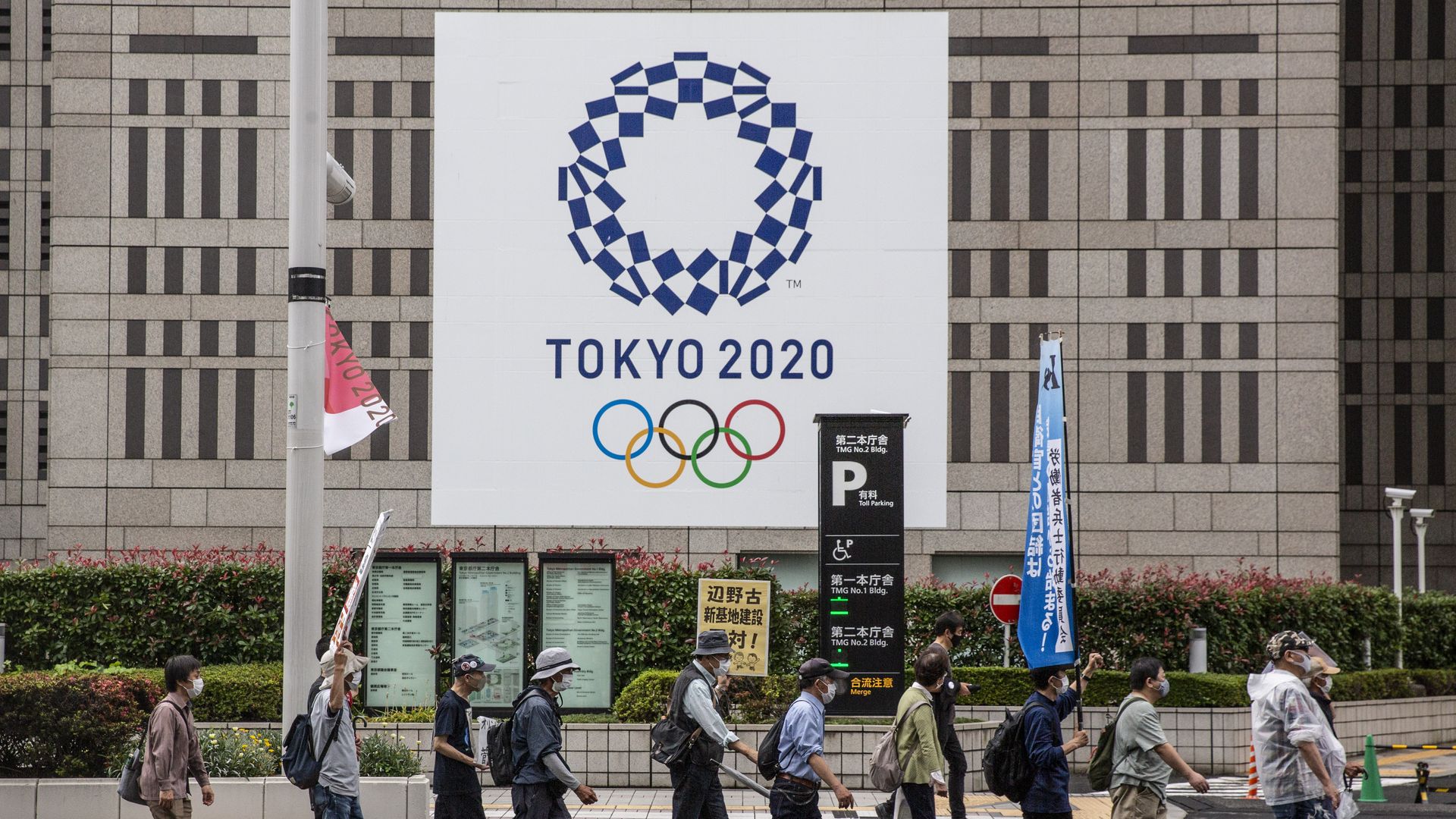 Protesters march in front of the metropolitan government building during a demonstration against the forthcoming Tokyo Olympic Games