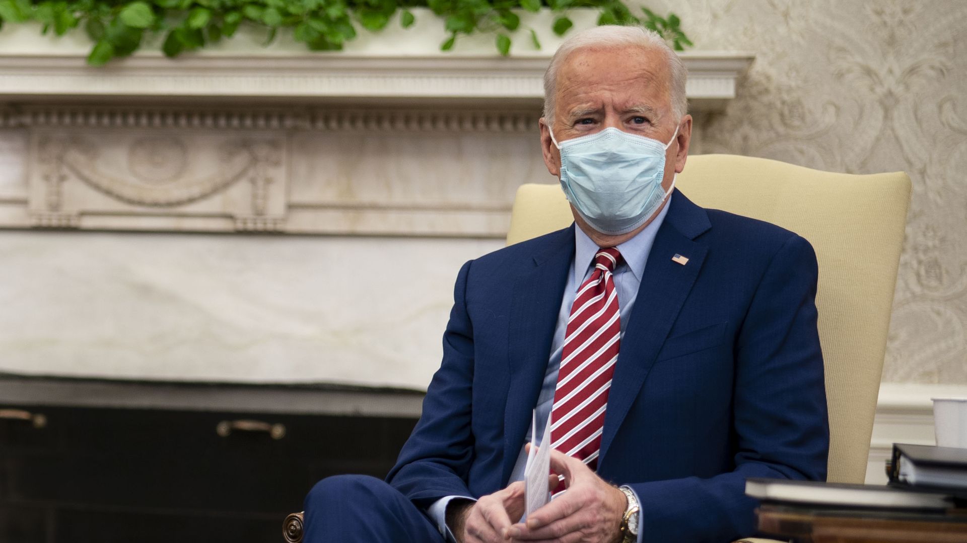President Joe Biden sitting on a chair wearing a mask