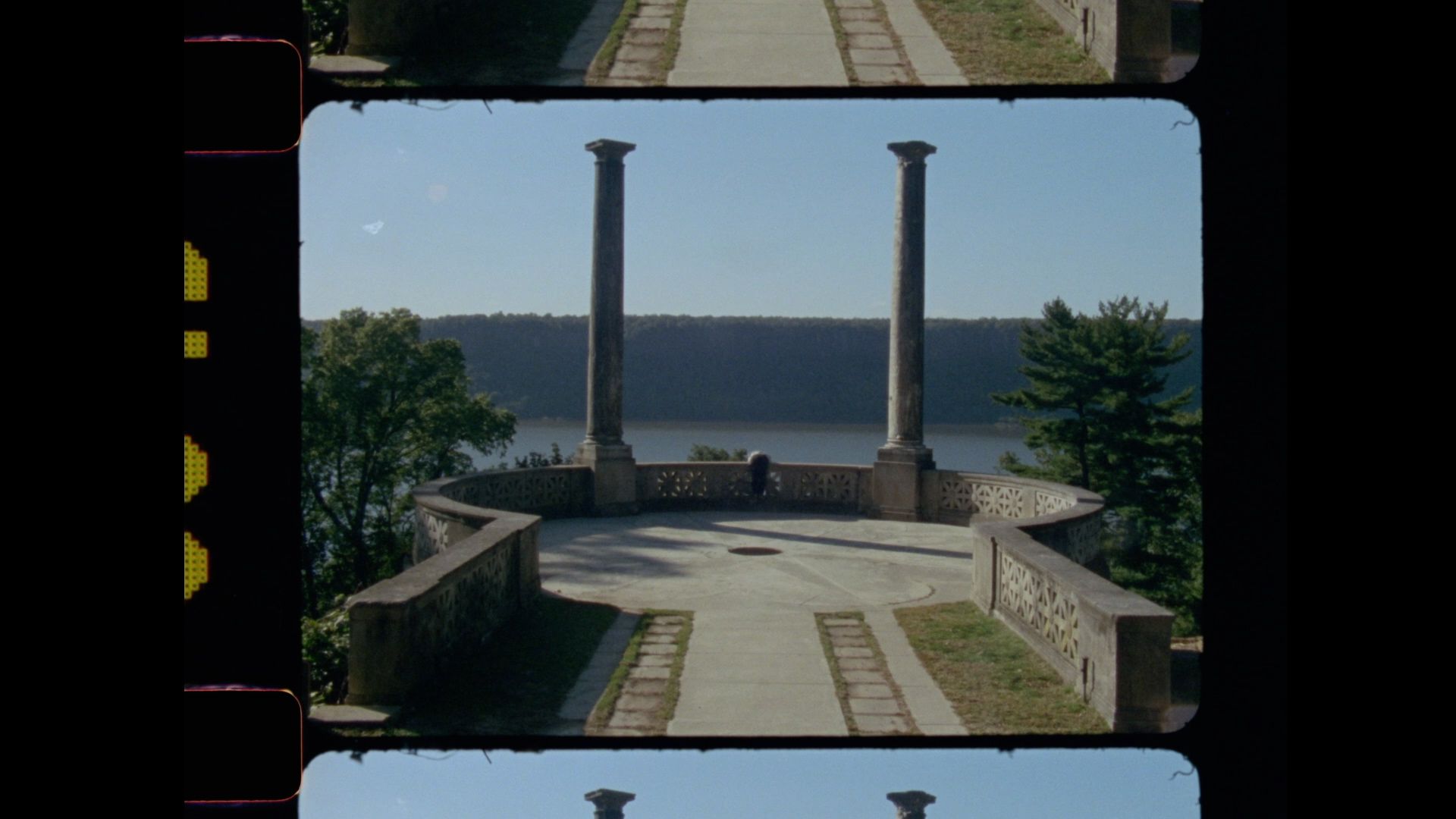 Still from a film with two columns in front of a courtyard.
