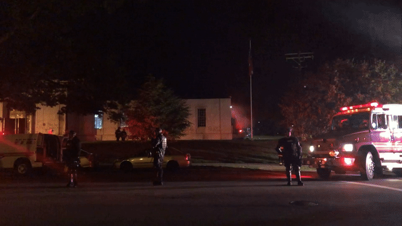 a video of a bunch of cops in front of a building. Red lights are flashing throughout the street