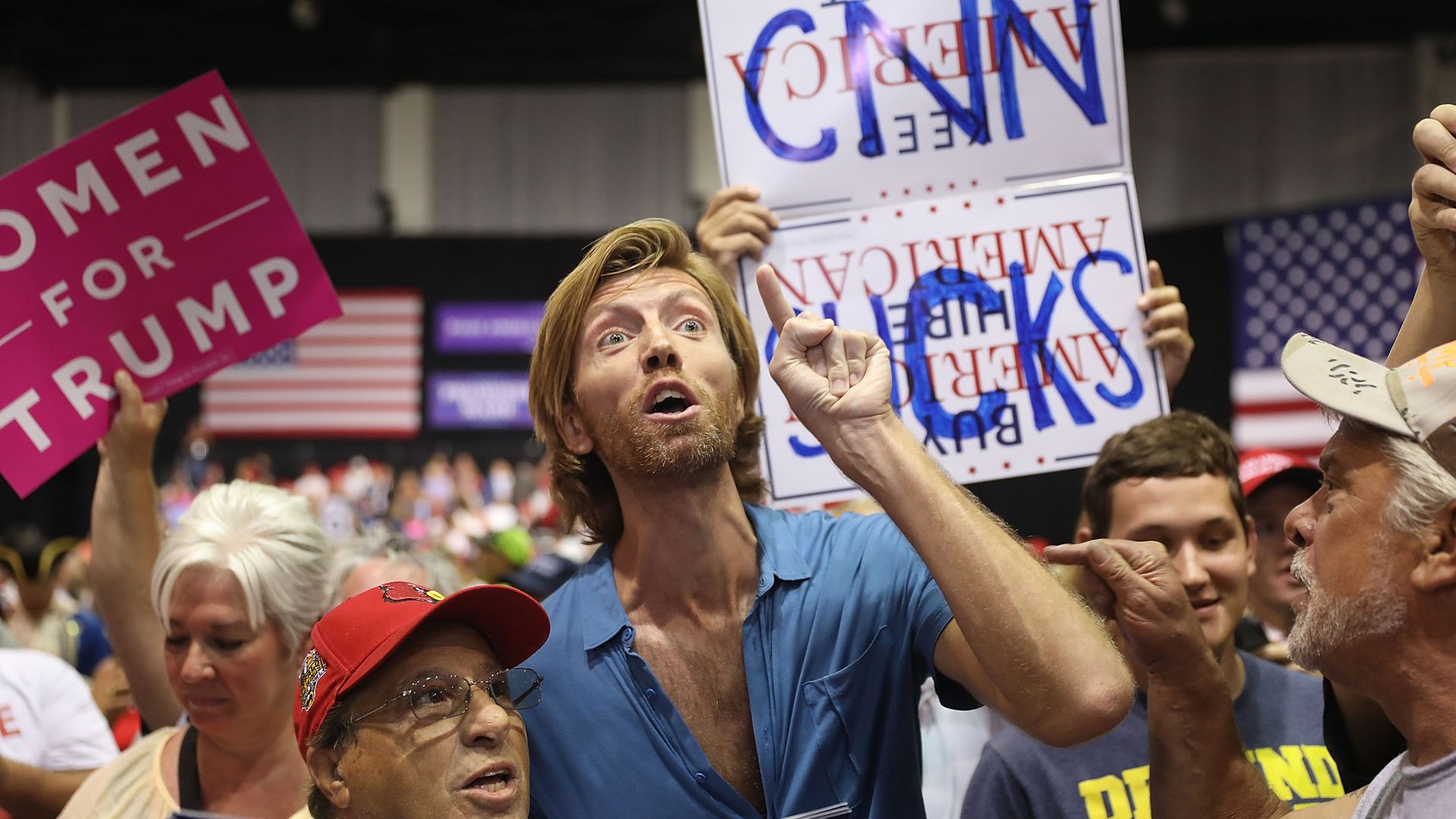 People at a Trump rally yelling, holding a sign that says "CNN SUCKS"