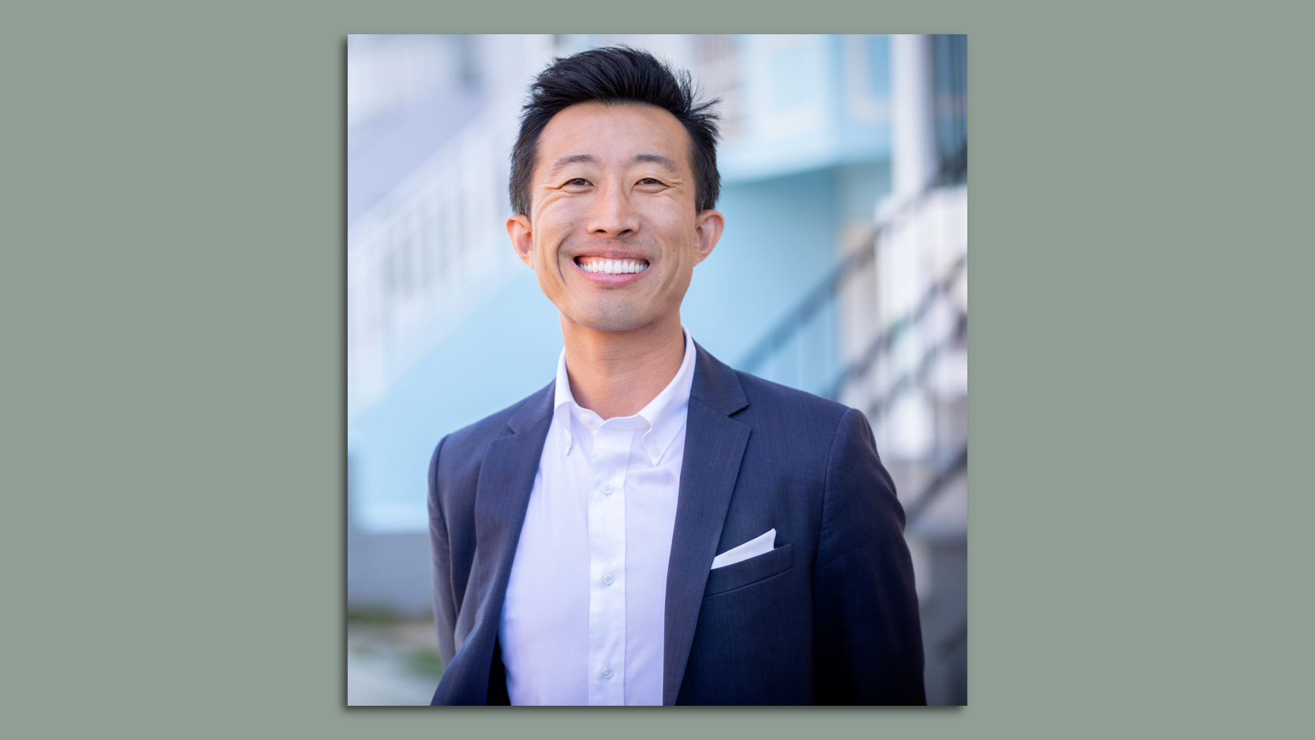 Photo of Michael Lai in a navy blazer and white collared shirt smiling at the camera