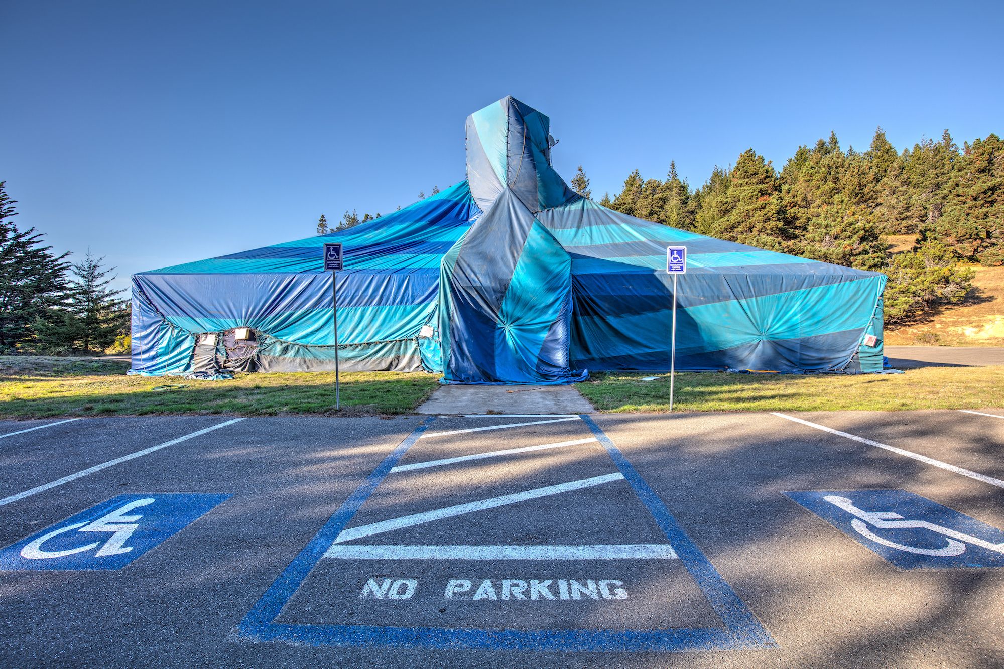 A building covered by a blue striped fumigation tent.