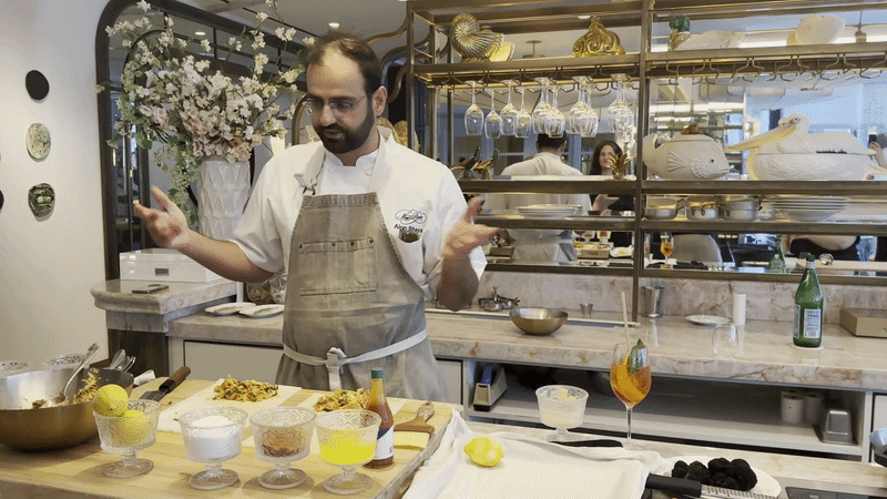 A chef speaks at a counter during a cooking demo.