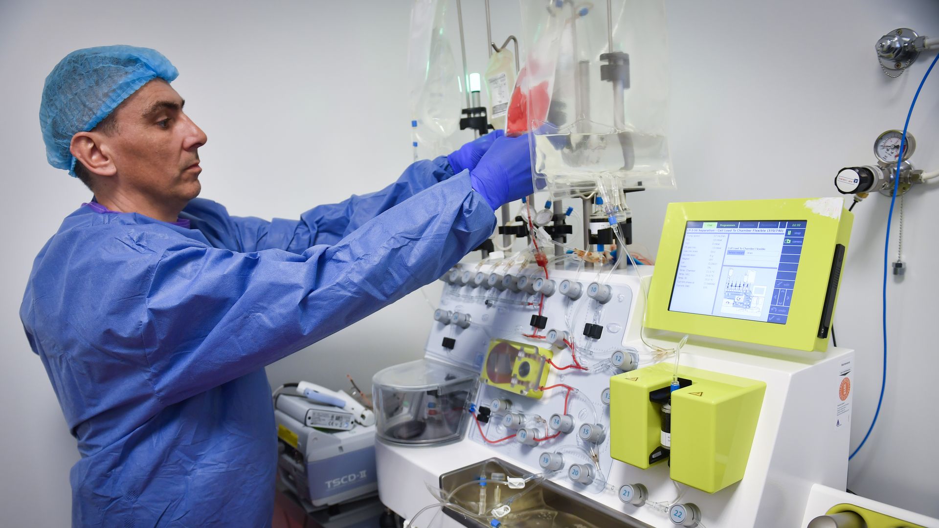 A lab tech handles a CliniMACS Prodigy automated device used for cell processing 