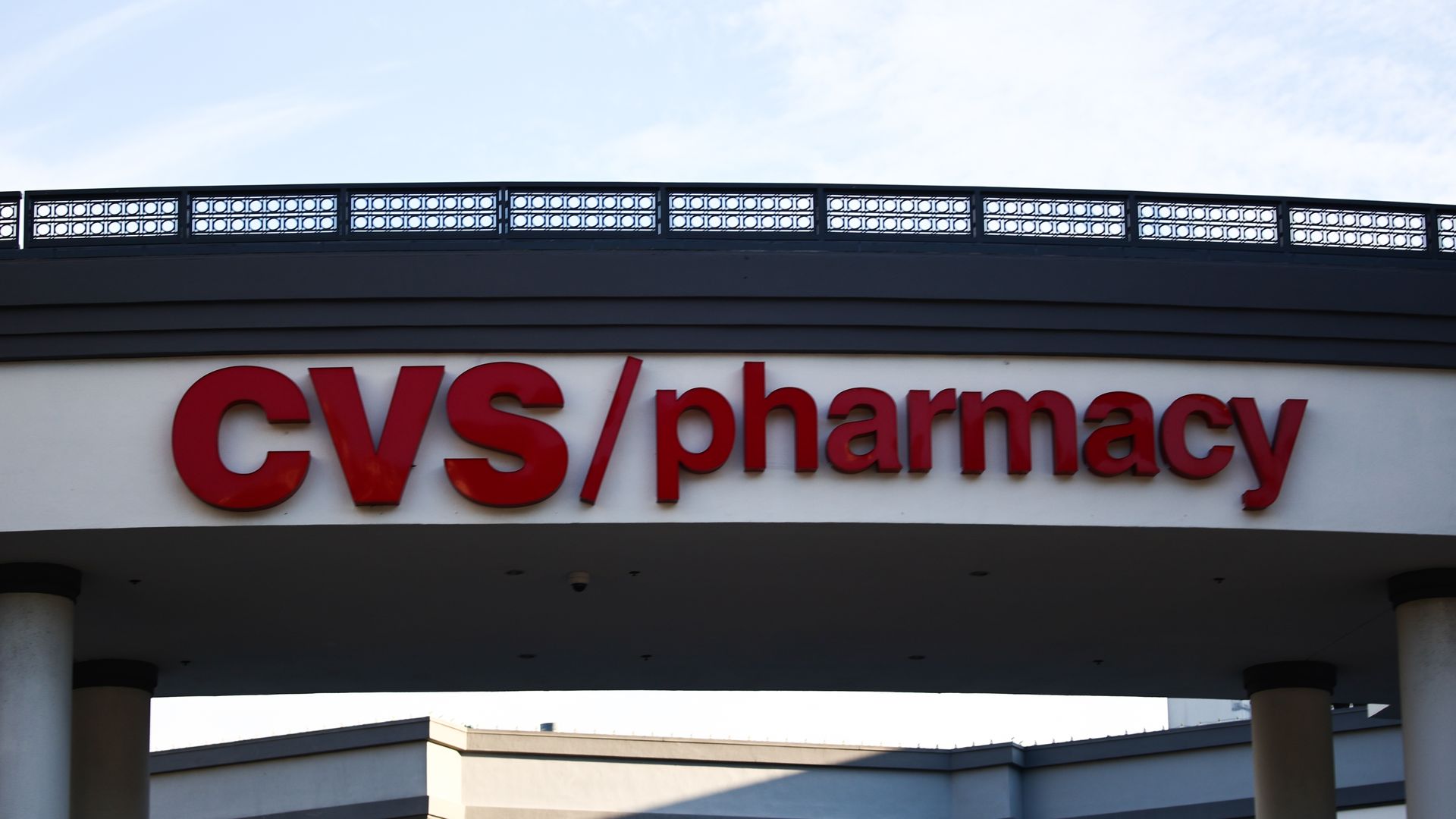A photo of the CVS Pharmacy sign outdoors with clouds in the background