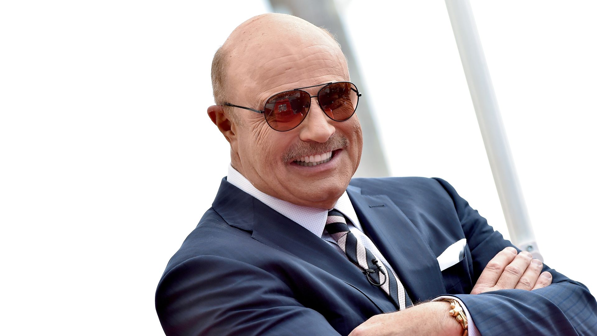 A man in a suit, wearing sunglasses, and his arms crossed