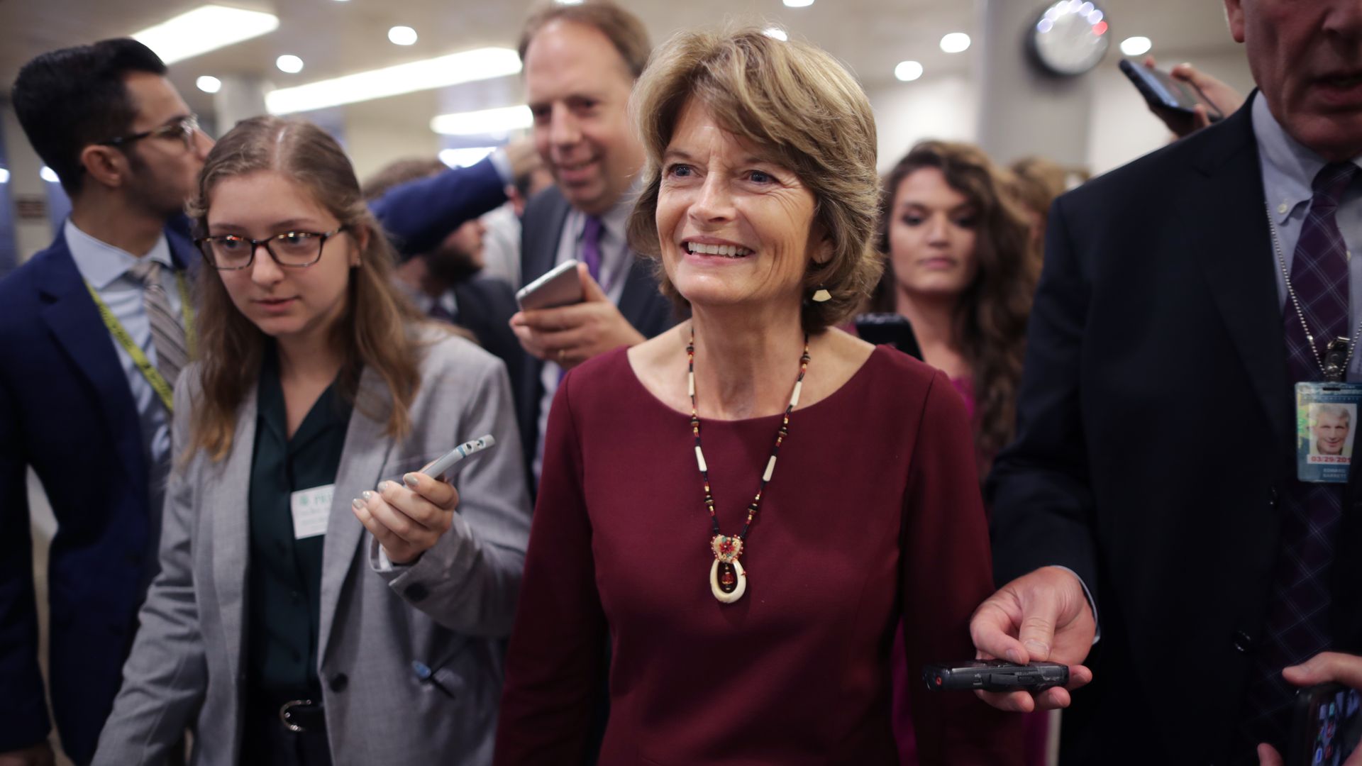 Lisa Murkowski smiling in the Capitol Hill basement surrounded by reporters.
