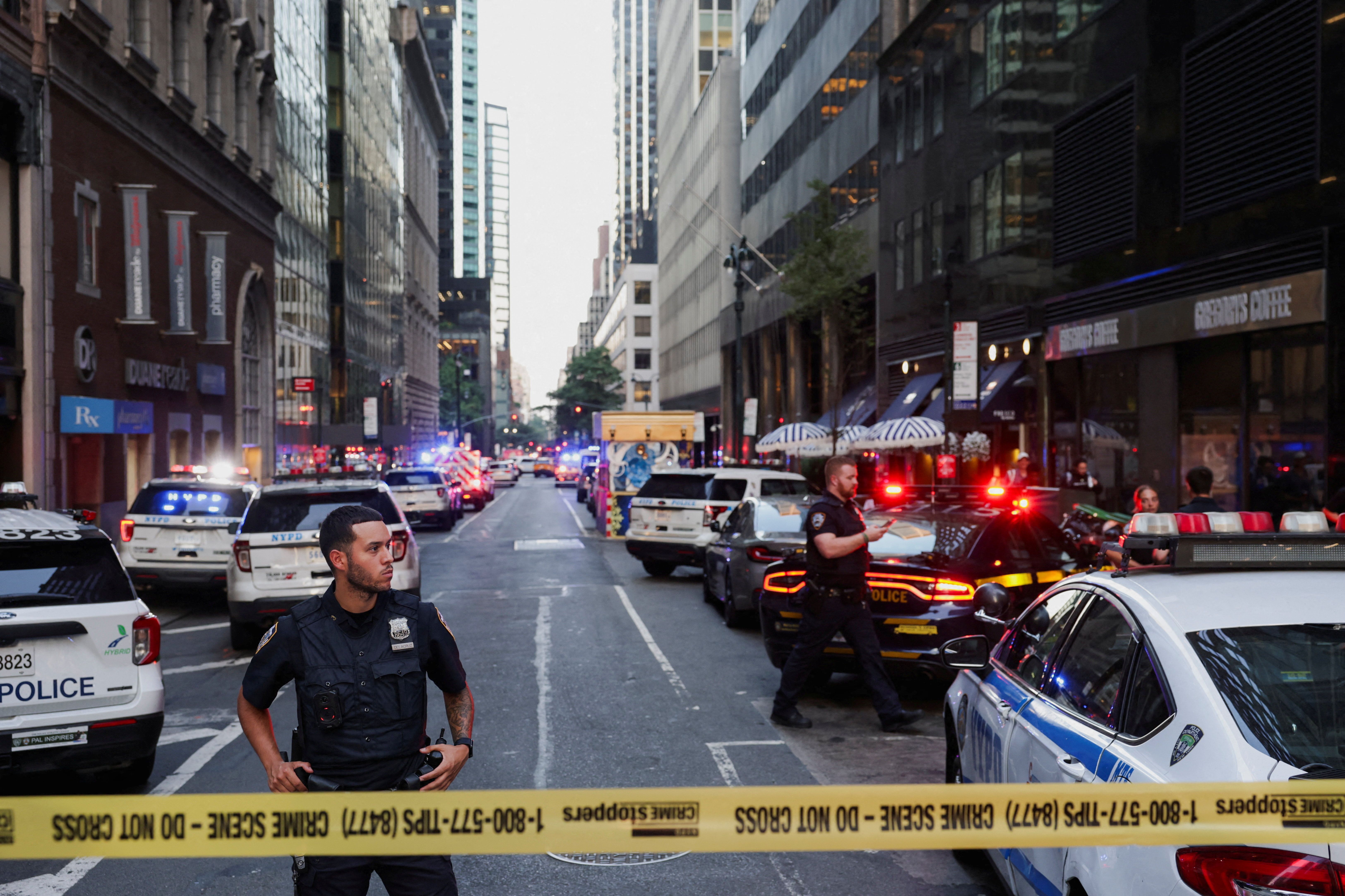 A police officer stands guard in a cordoned-off area after a shooting in a midtown Manhattan office building.