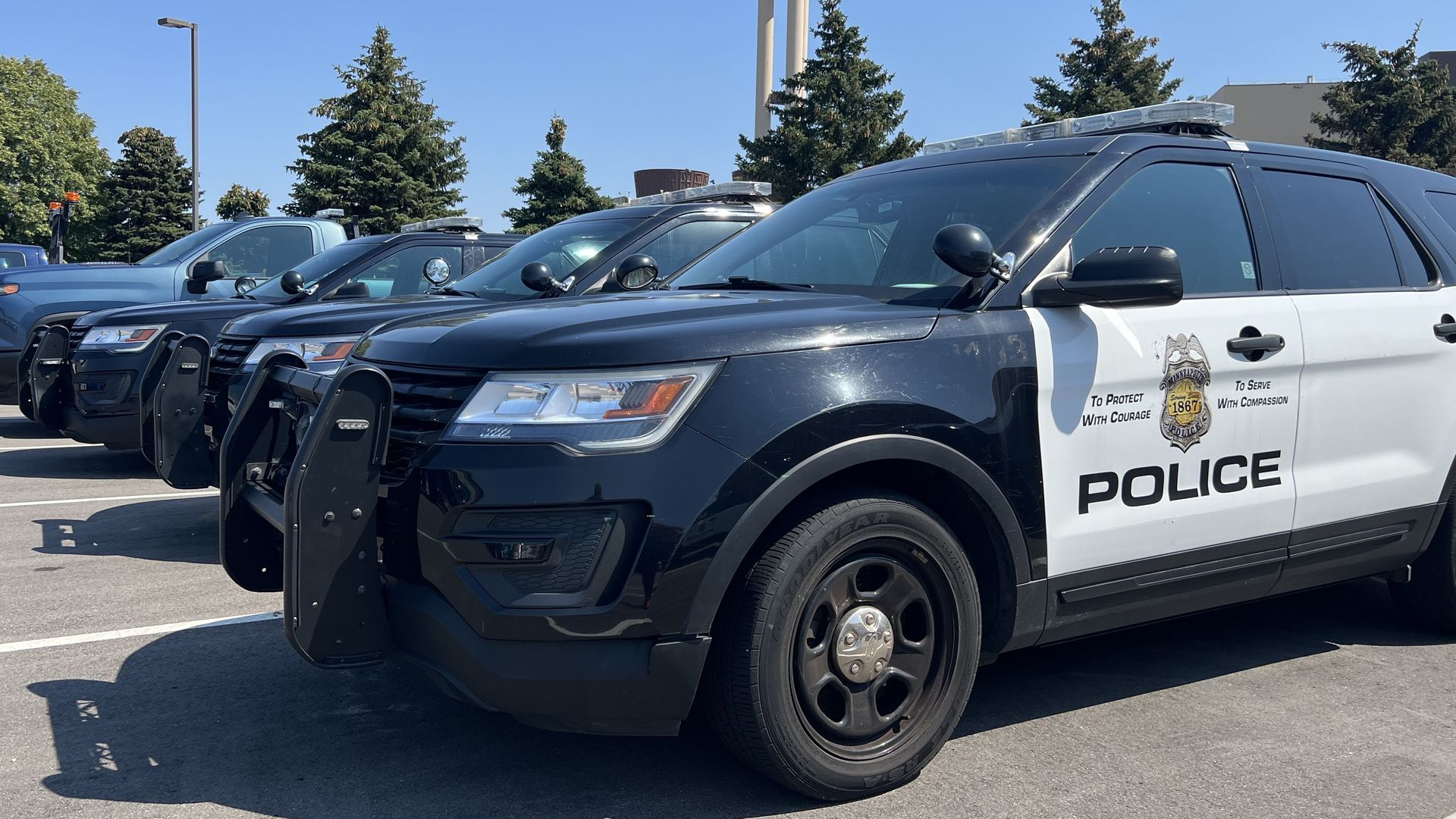 Black-and-white police SUV squads lined up in a parking lot