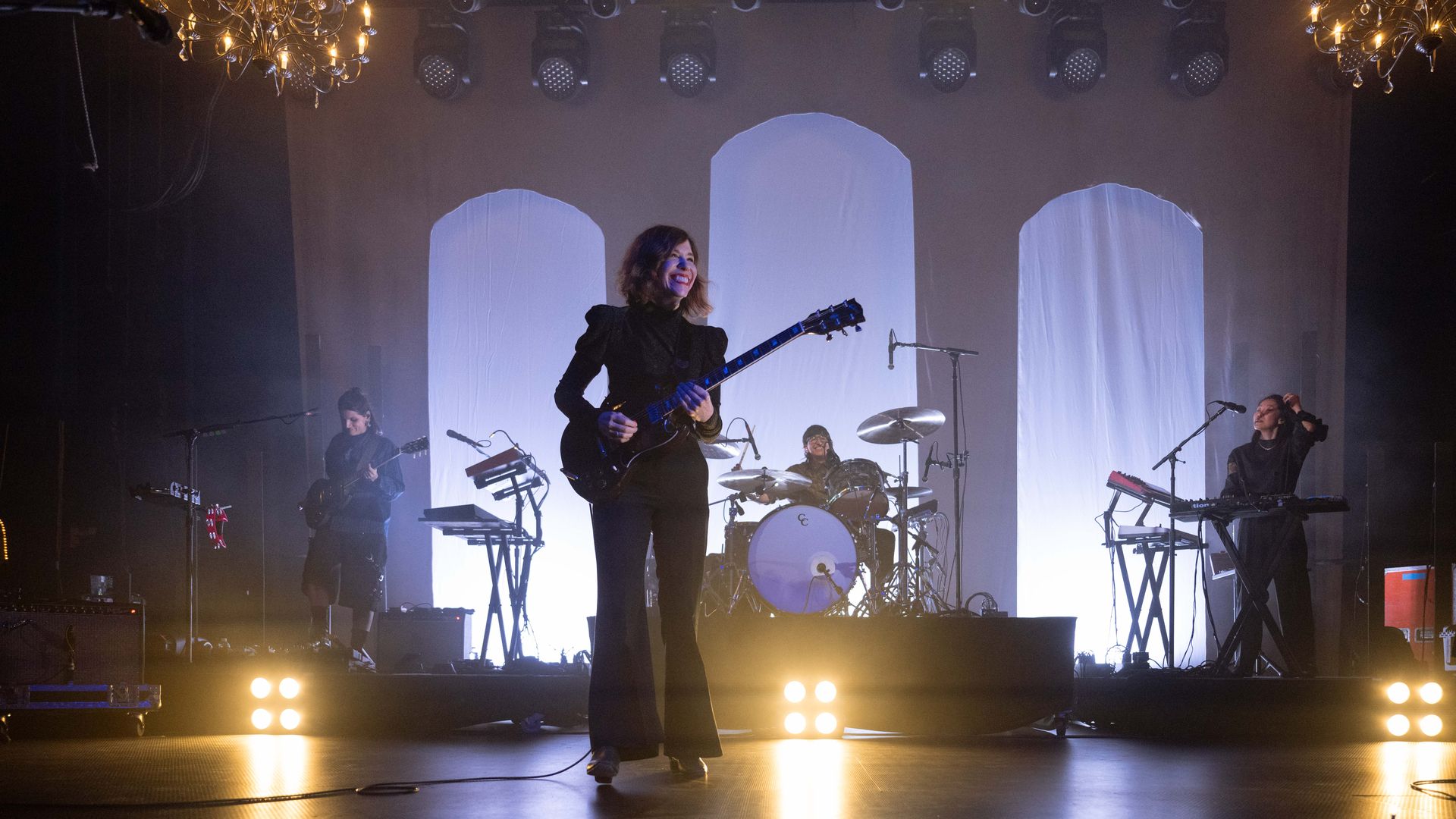 A band plays instruments on a dimly light stage.