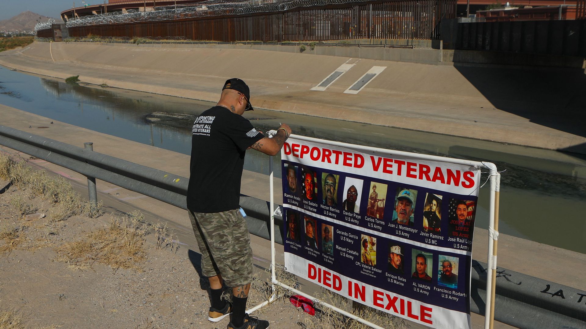 Ivan Ocon, a Mexican veteran of the U.S. Army deported to Mexico, ties a banner with pictures of deported veterans who died outside the US in front of the border wall in Ciudad Juarez, Mexico.