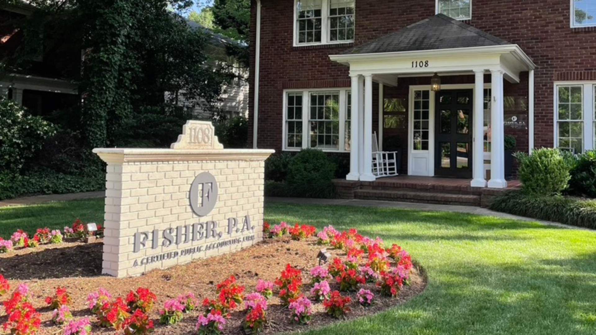 Brick office building with white columns and a black door numbered 1108, sign in front reads 