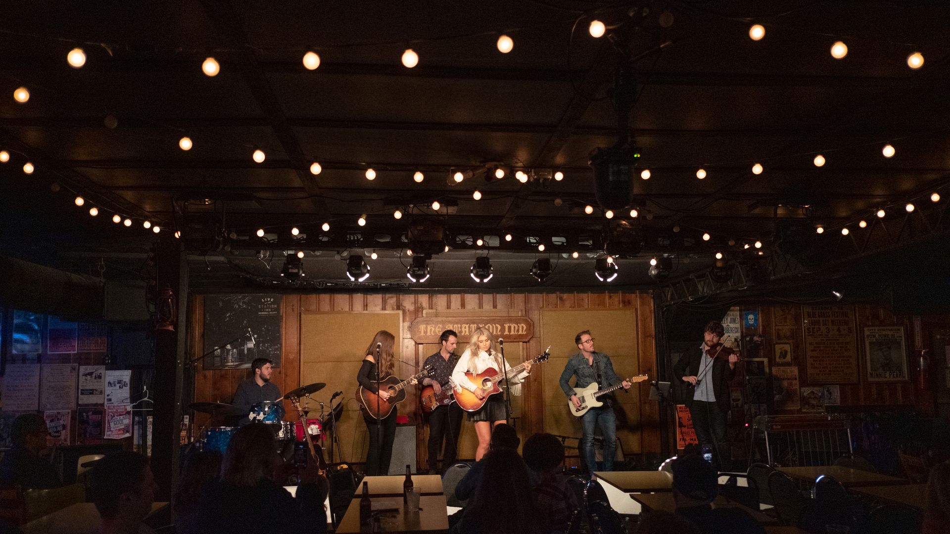 A band performs on stage in a dark room