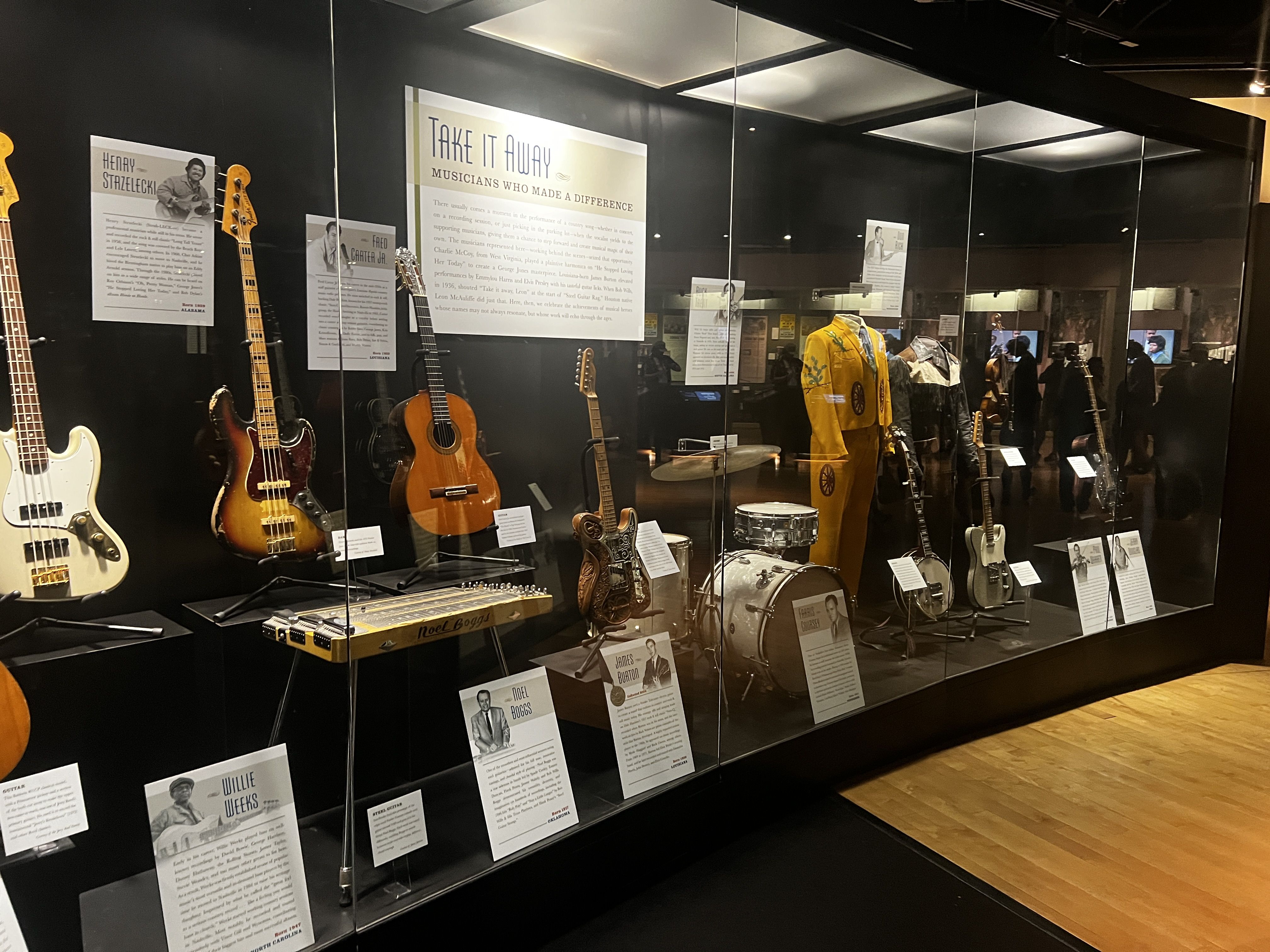 Guitars and artifacts behind a glass case. 