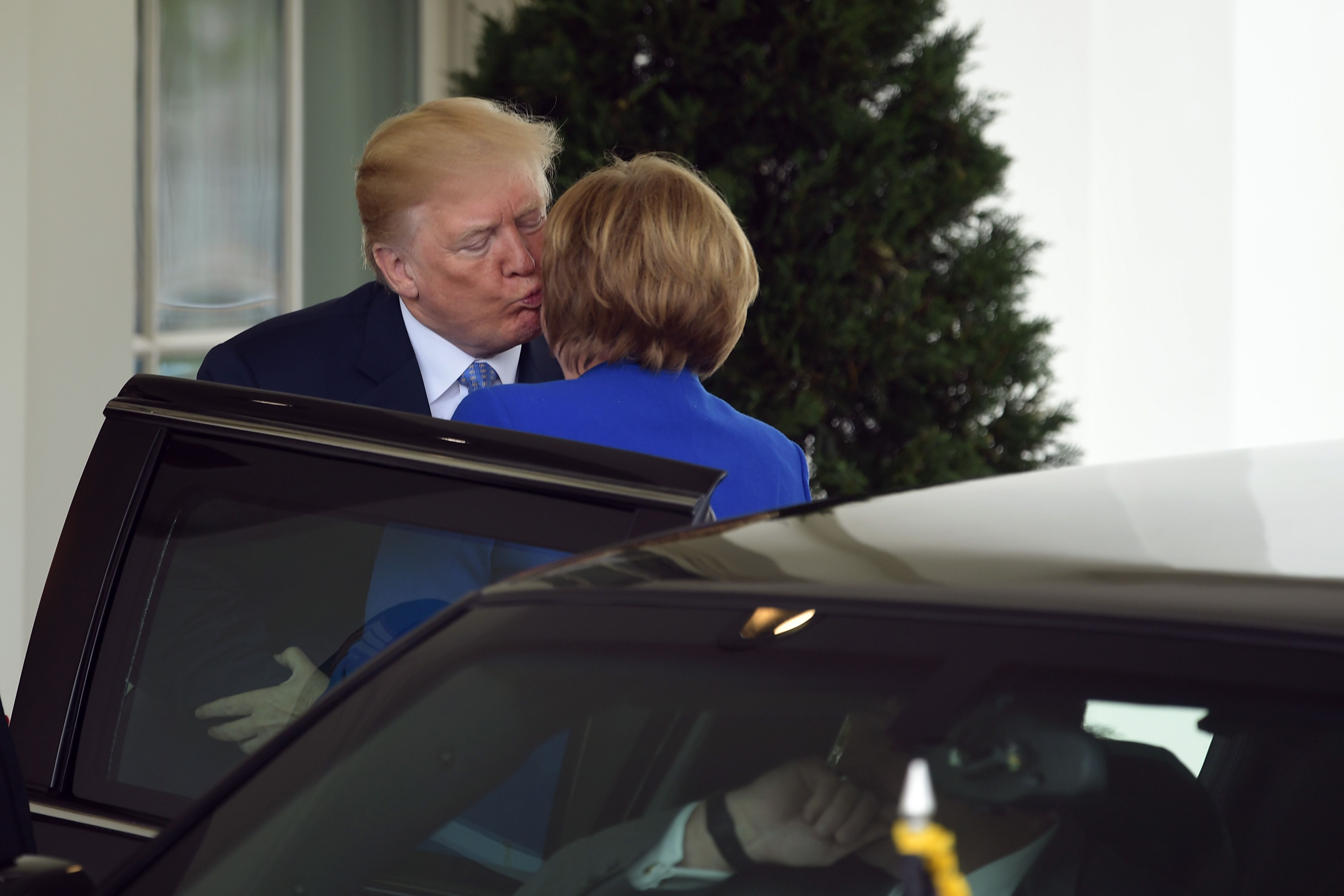 Trump kisses Merkel on a cheek.