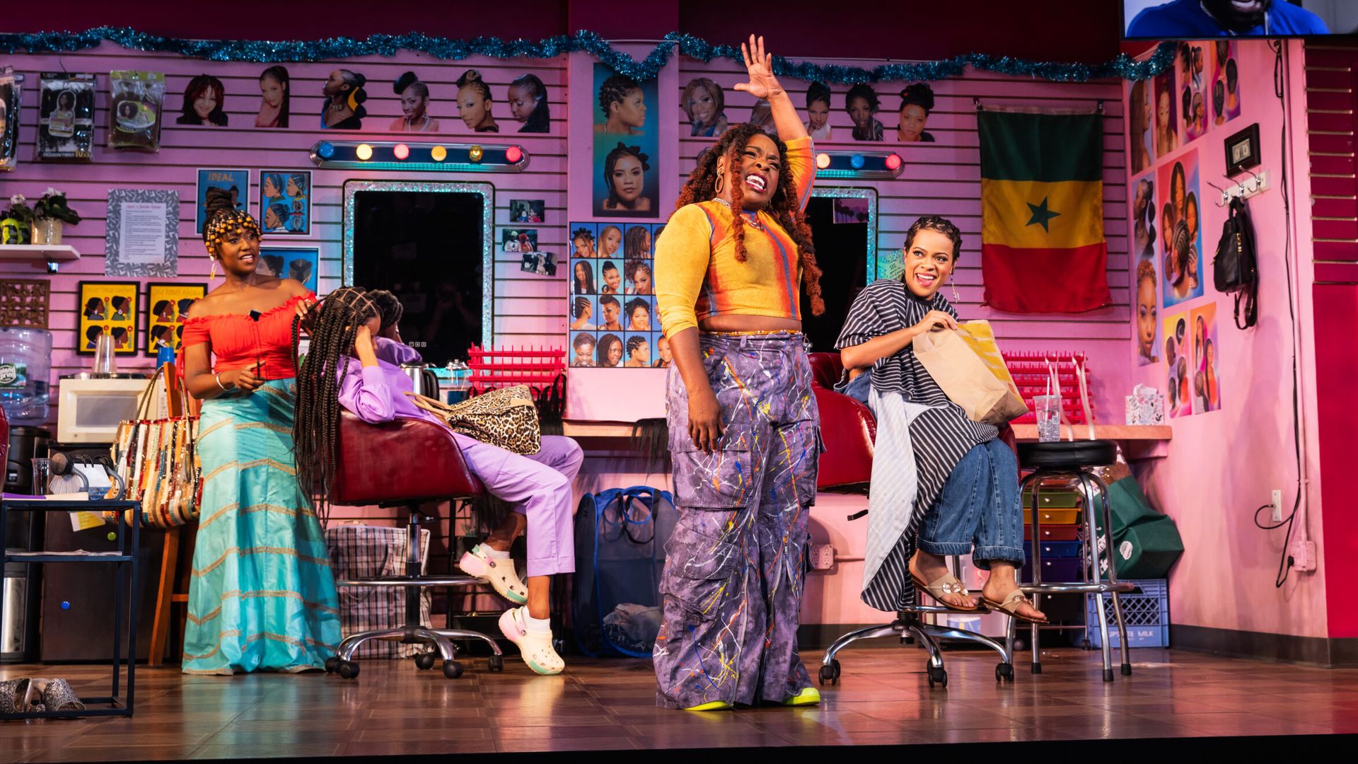 Photo of four performers on a stage set that represents a braiding salon