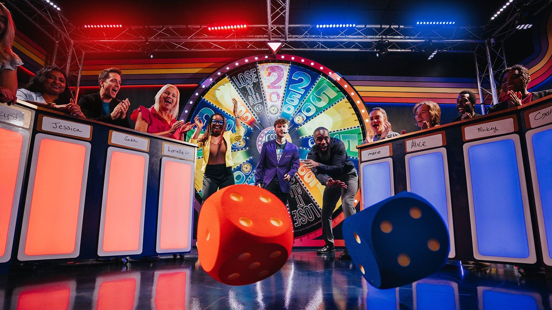 Colorful game show set featuring a large spinning wheel, cheering contestants behind numbered panels, and red and blue dice rolling toward a shiny floor.