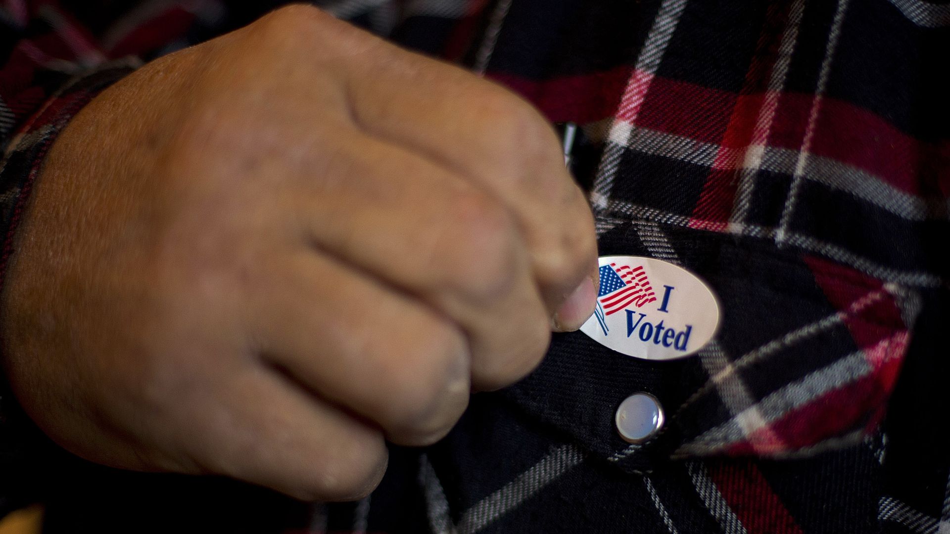 Man affixes an "I voted" sticker. 
