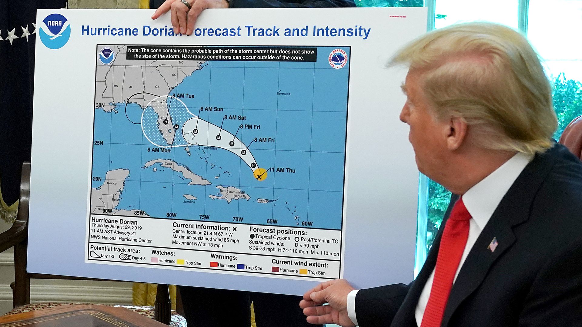 In this image, Trump looks at a NOAA map that depicts the path of Hurricane Dorian across the U.S.