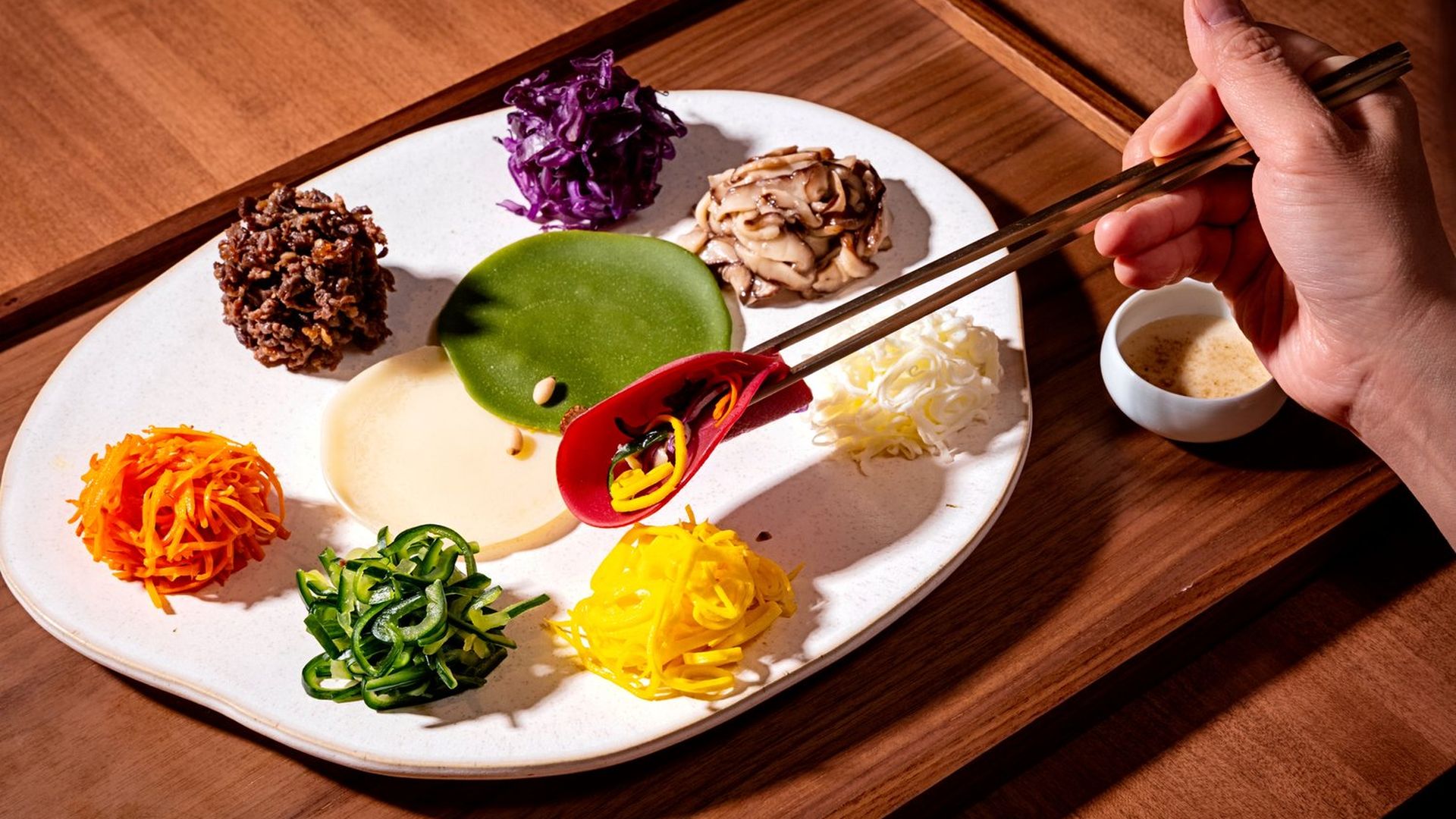 A white plate with seven colorful Korean "delicacies" and thin crepes for wrapping at Onggi 