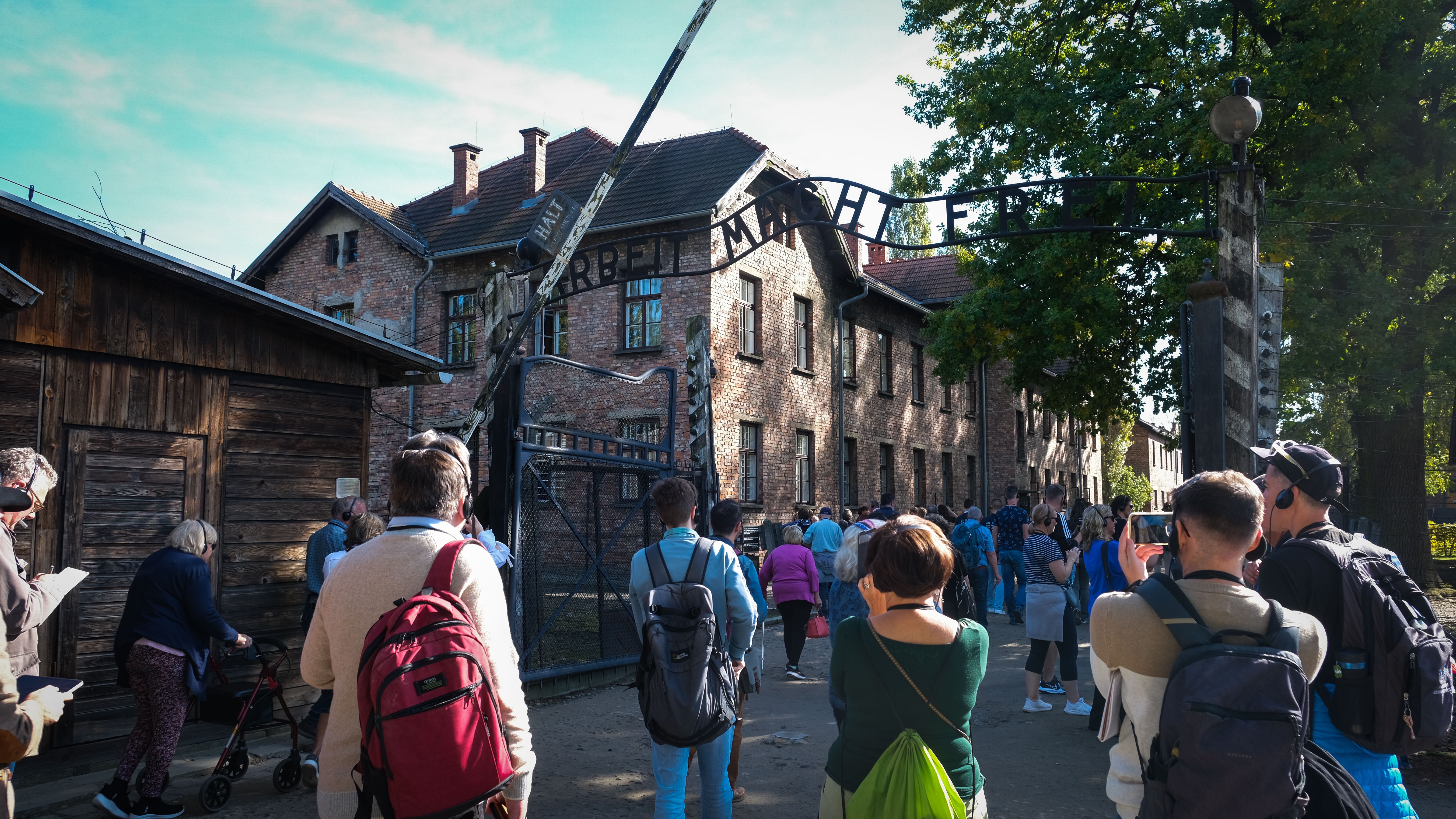 Visitors take photos to the enterance of Auschwitz-Birkenau with the motto above the gate, Arbeit macht frei (Work Sets You Free).