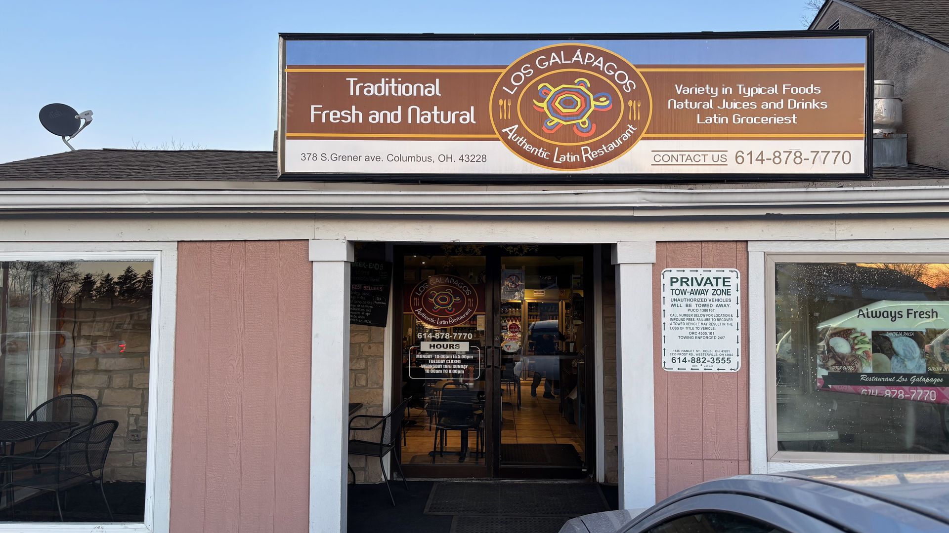 The exterior of Los Galápagos restaurant, with a pink facade and sign that reads "traditional fresh and natural" and "authentic Latin restaurant"
