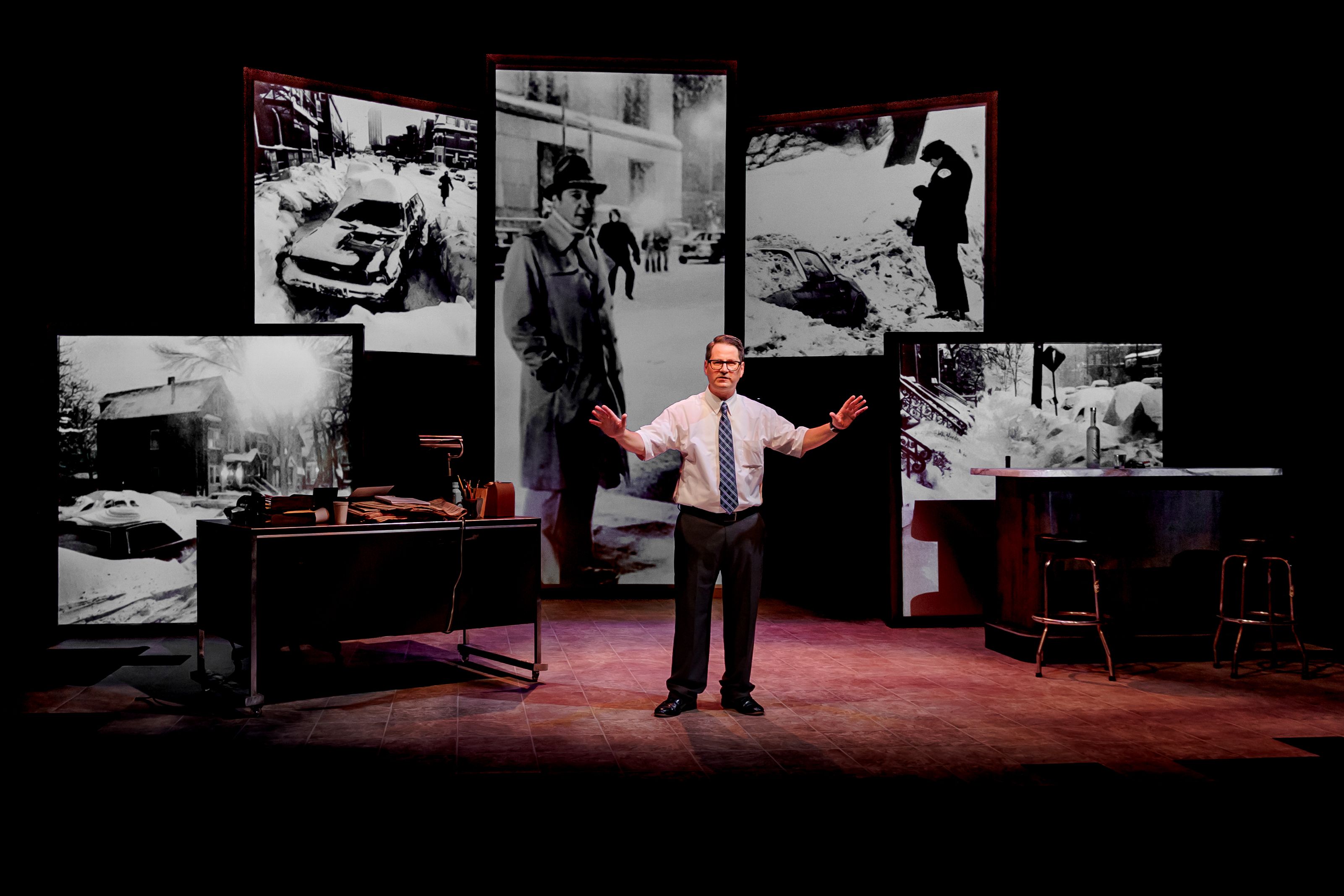 Photo of a man in a tie on stage in a play