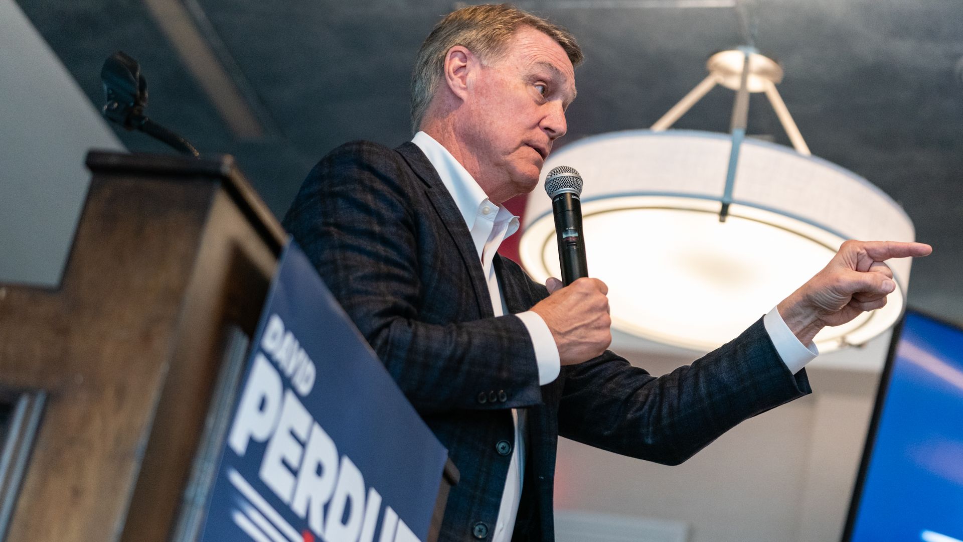 David Perdue at a podium pointing with microphone