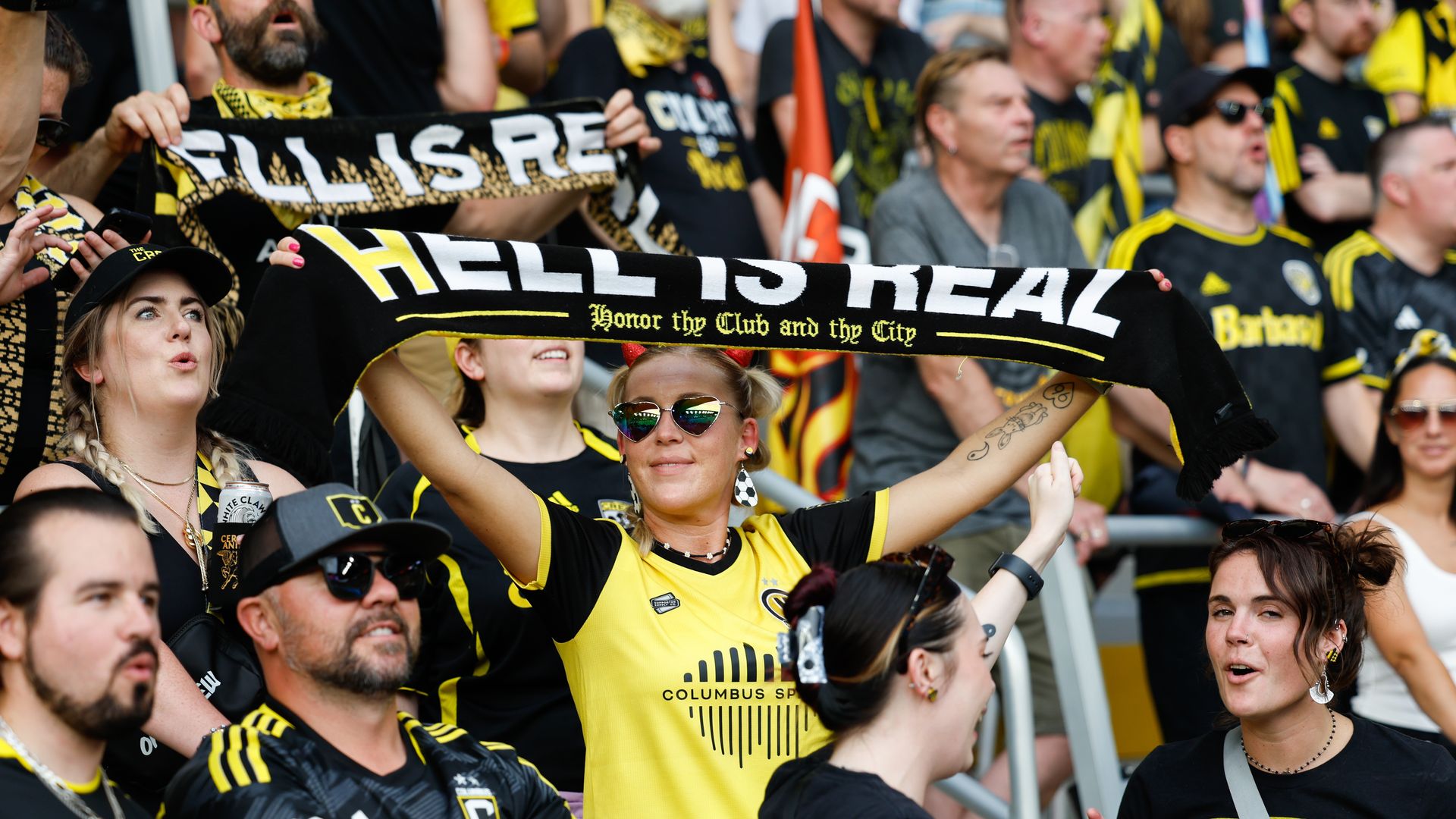 A Columbus Crew fan in the home crowd holds up a scarf that says "Hell is Real"