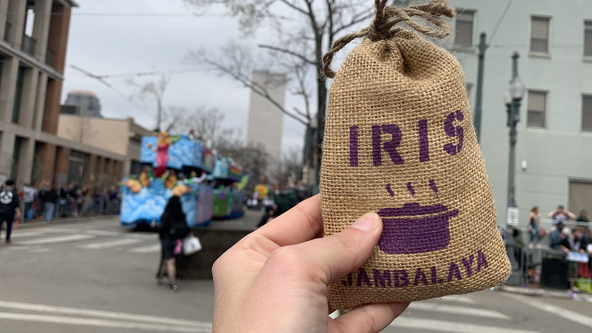 A hand holds up a small brown bag of jambalaya mix labeled with Iris.
