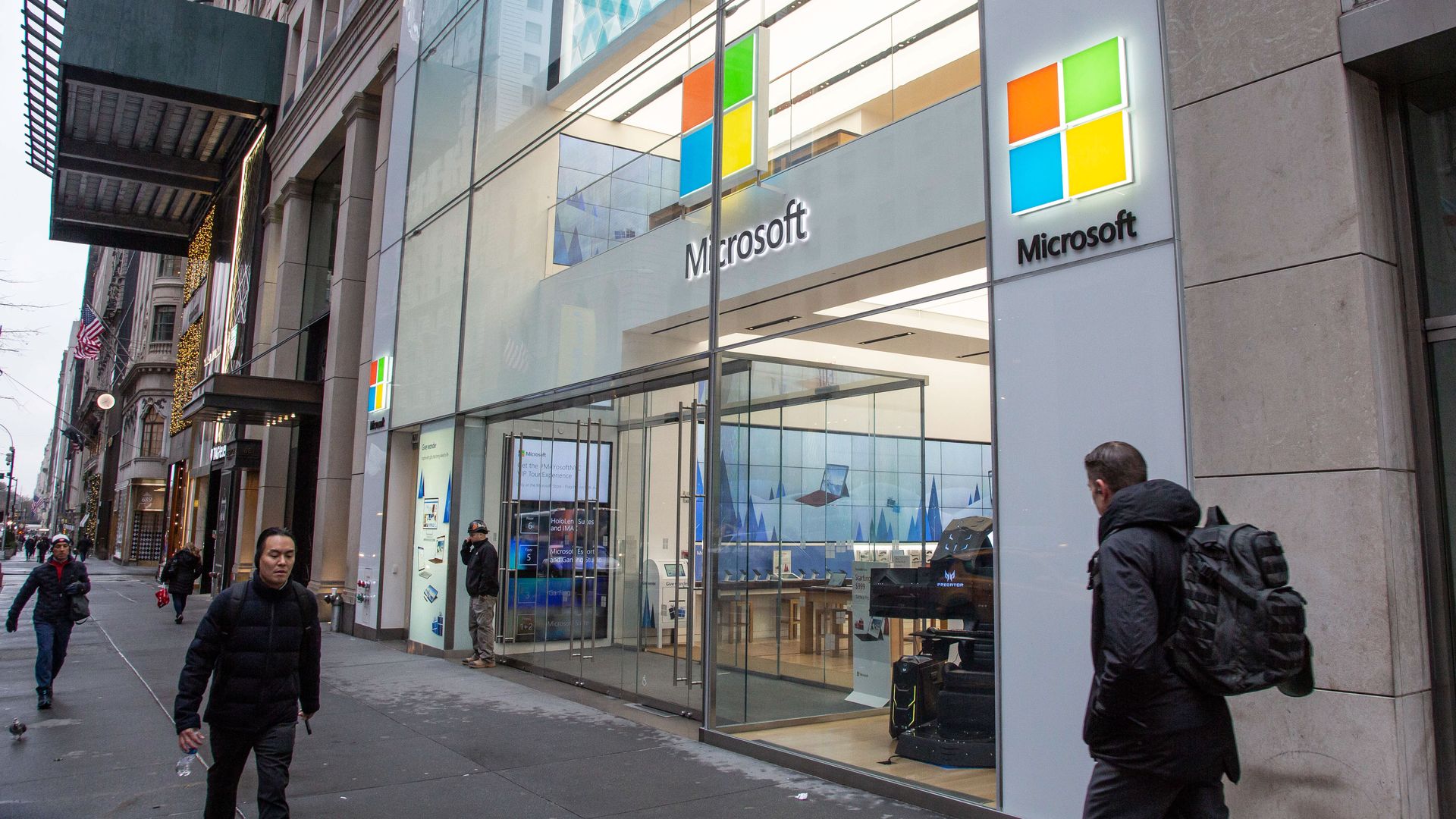 People walk past a Microsoft store entrance with the company's logo on top in midtown Manhattan