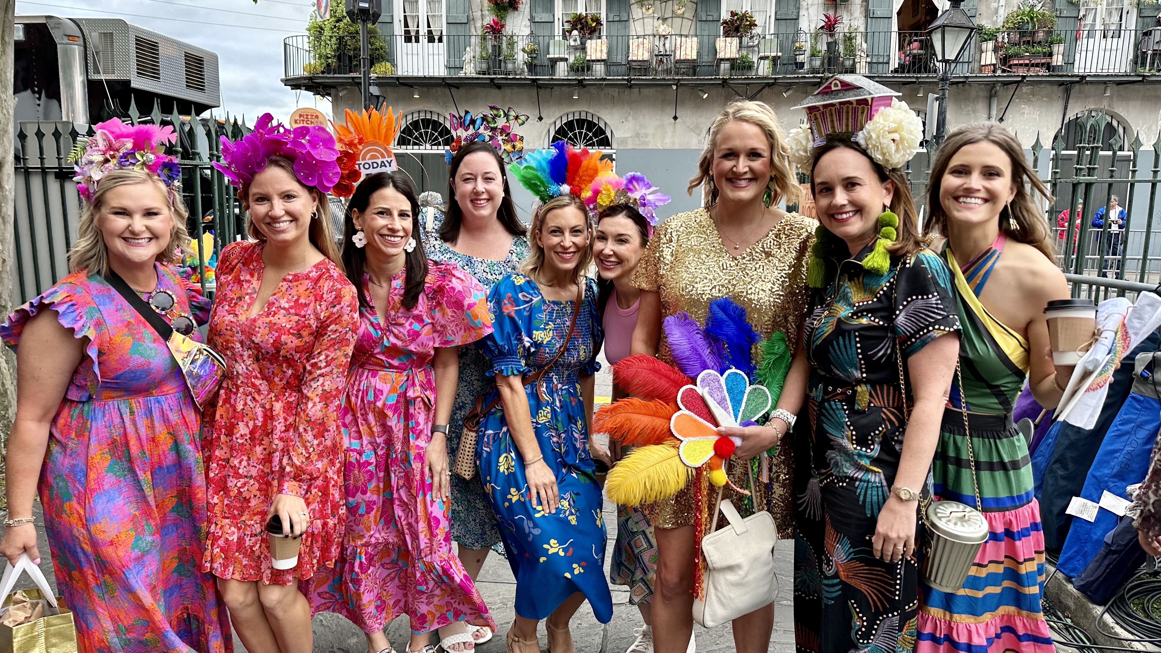 Photo shows a group of women in colorful dresses and head pieces.
