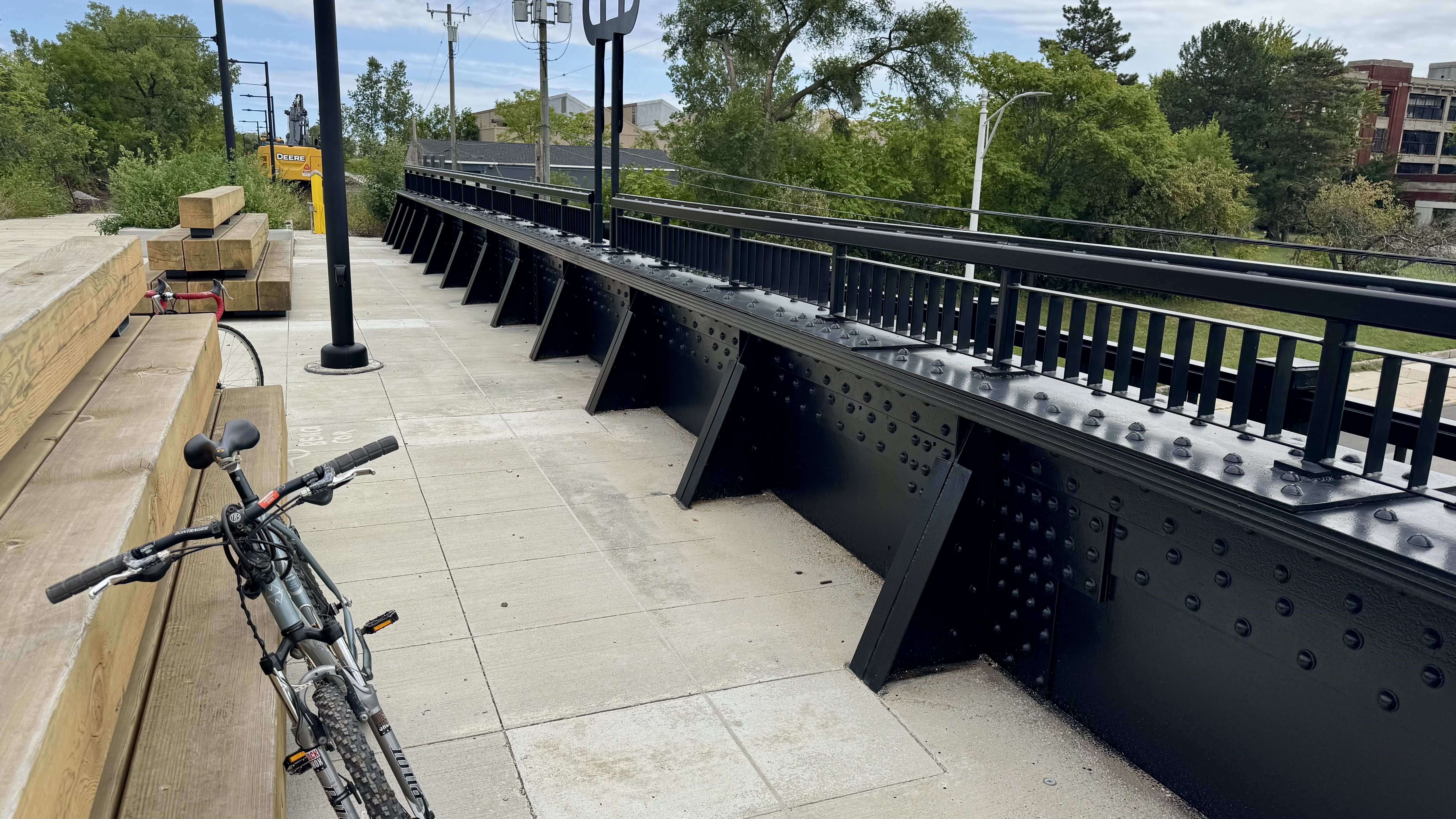 A bike rests against a bench on a bridge overlooking a highway