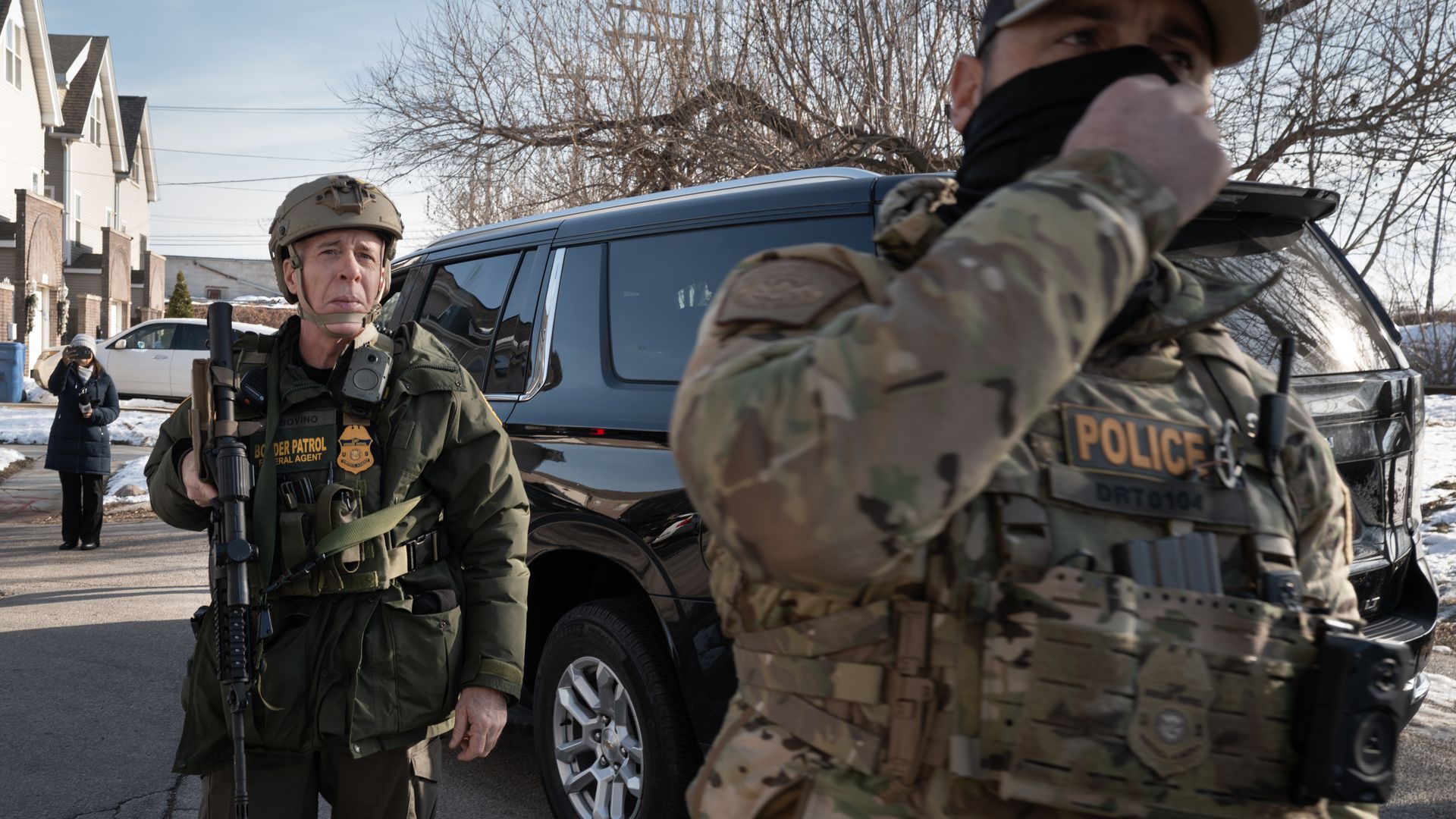 Man in camouflage and helmet in a city with a car in the background 