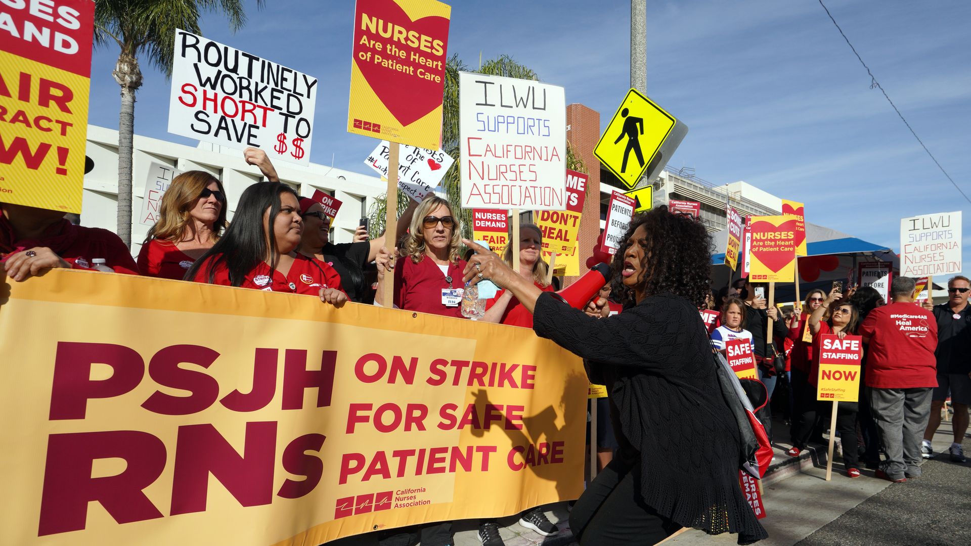 Nurses stand on a street holding signs and chanting during a strike.