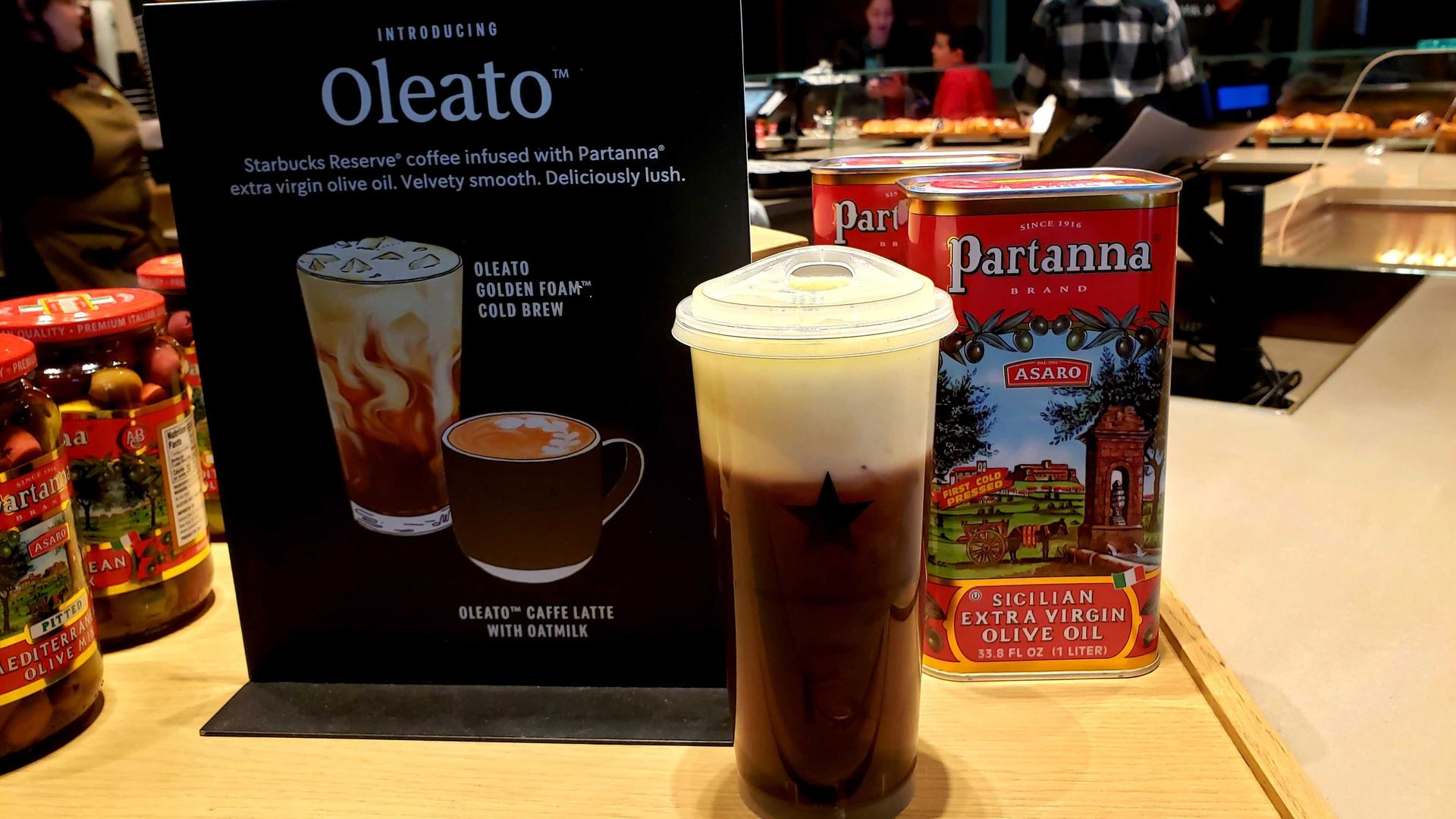 Photo of a cup of coffee in front of a book and can of olive oil