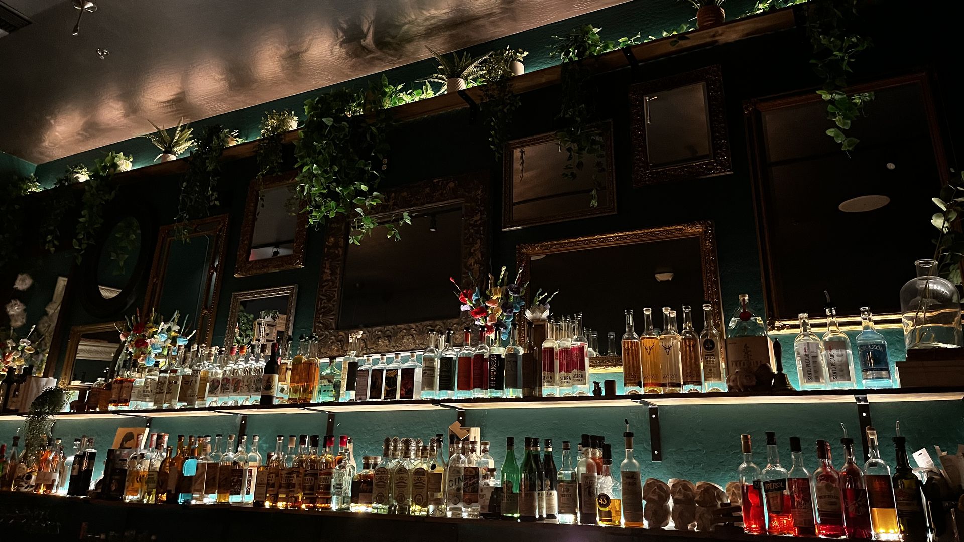 A bar with moody lighting and rows of alcohol bottles. 