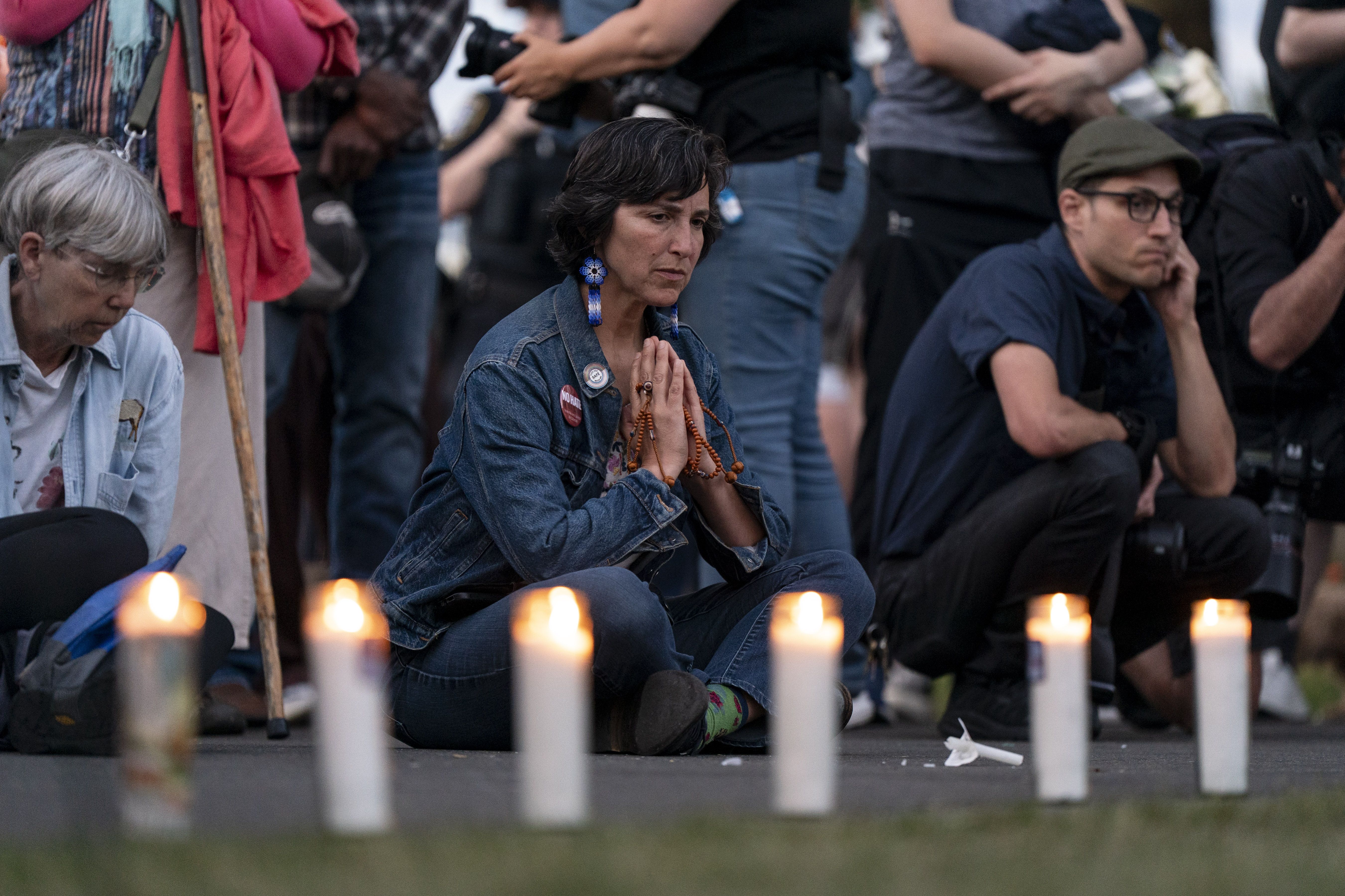 People gather in front of a row of candles to remember the victims of the Seattle Center shooting. 