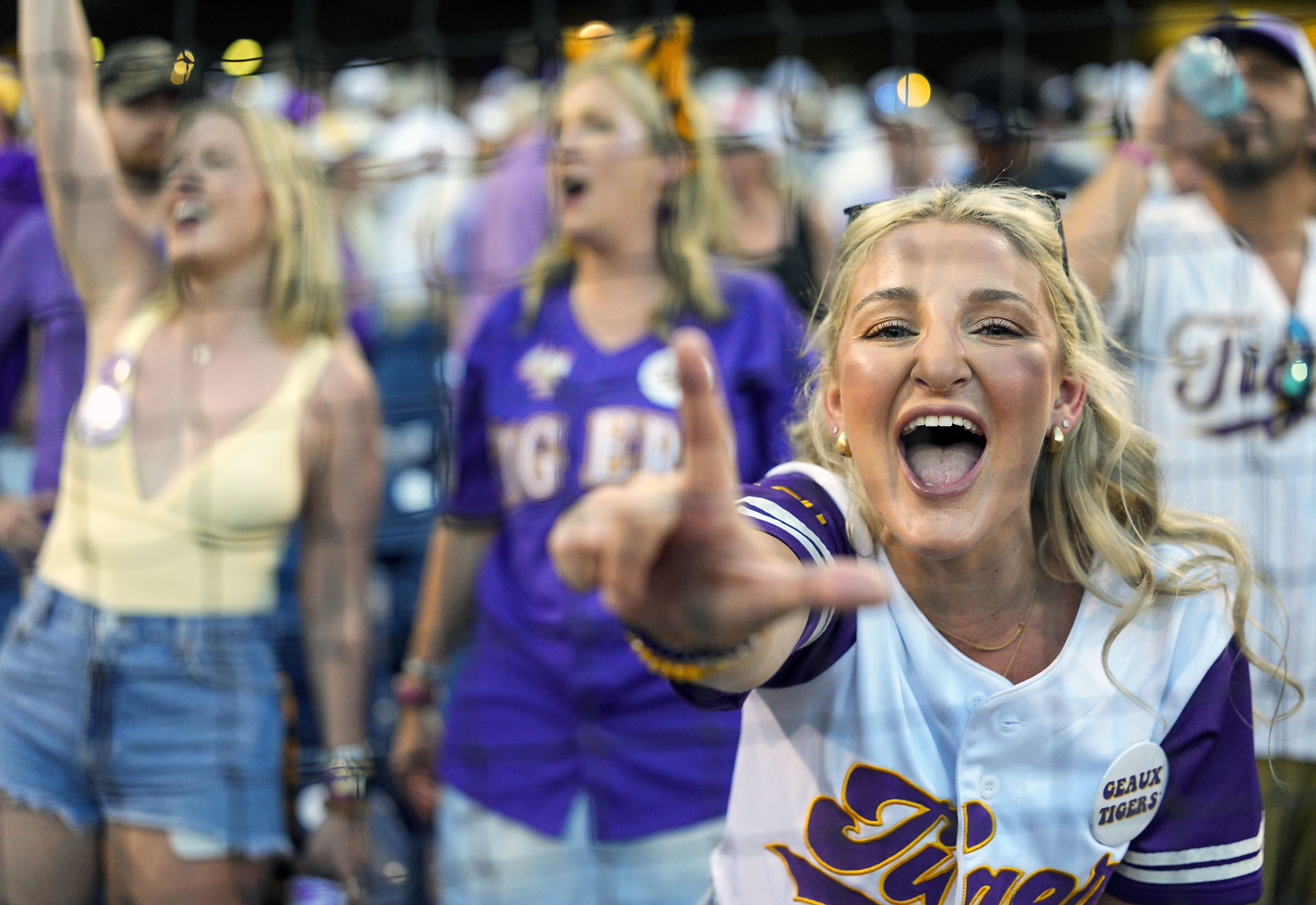A woman makes an L-shape with her hand as she cheers on the baseball team.