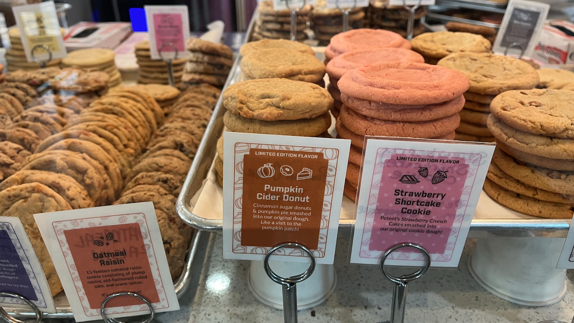 Stacks of cookies with artsy labels in front of them showing the flavors. In the center is pumpkin cider donut cookie.