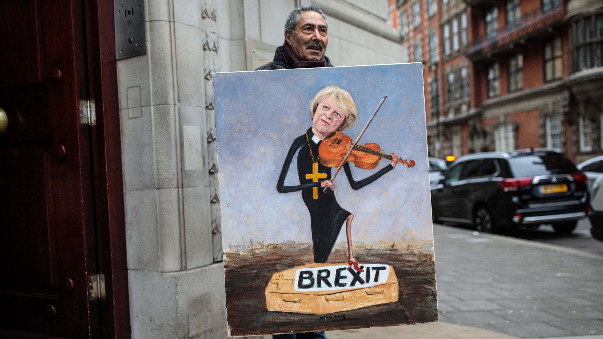 Political artist Kaya Mar stands with his painting depicting Prime Minister Theresa May playing a violin outside Millbank Studios in Westminster on January 16, 2019 in London, England. 