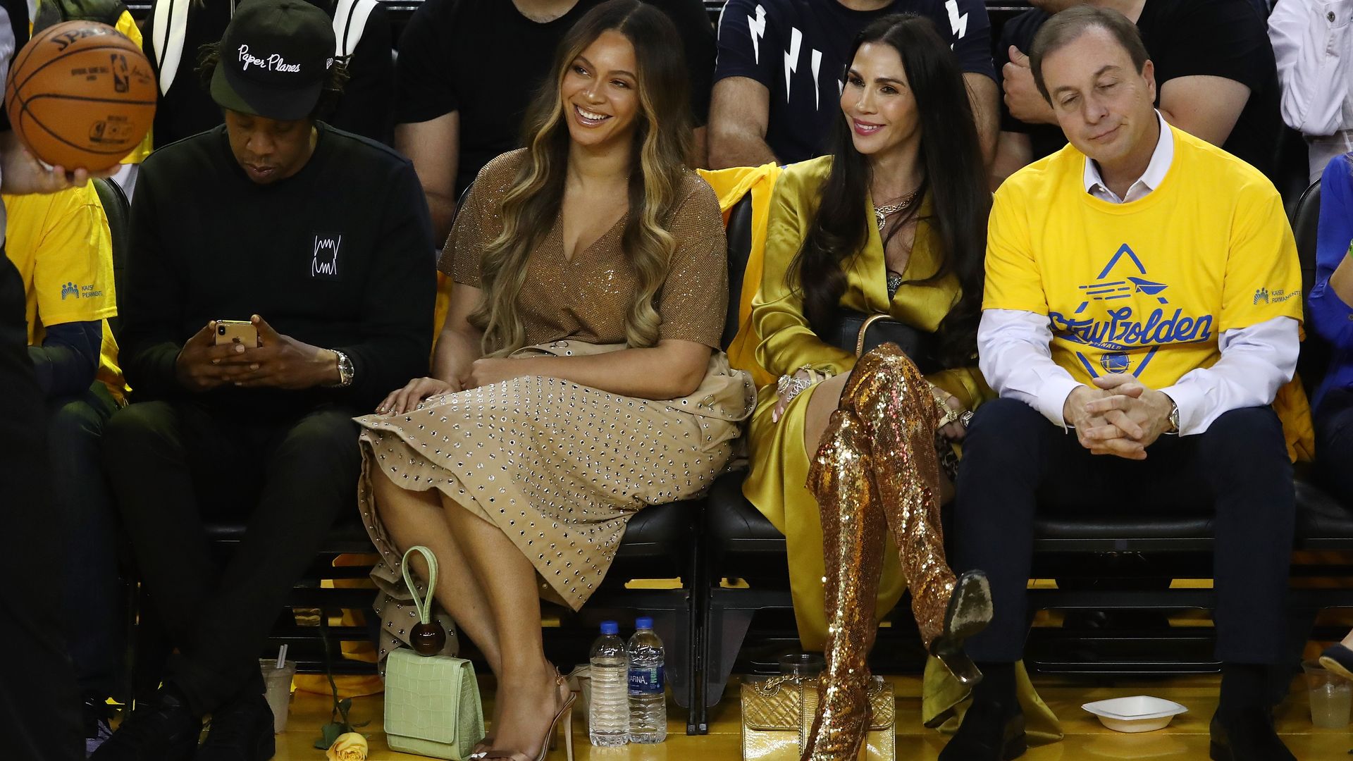 In this image, Beyonce sits next to others on a courtside basketball game.