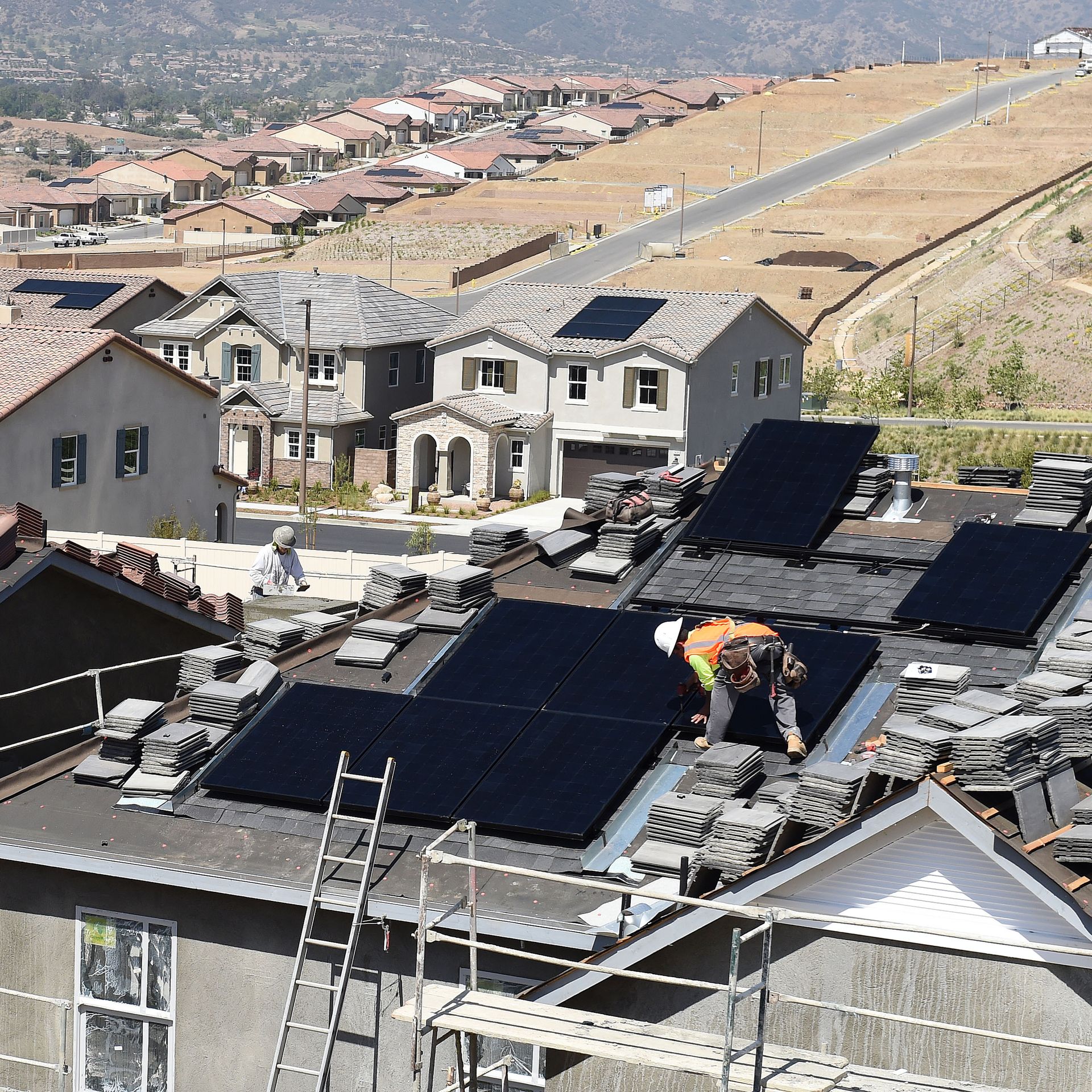 Workers install solar panels on the roofs of homes under construction south of Corona Thursday morning May 3, 2018. 